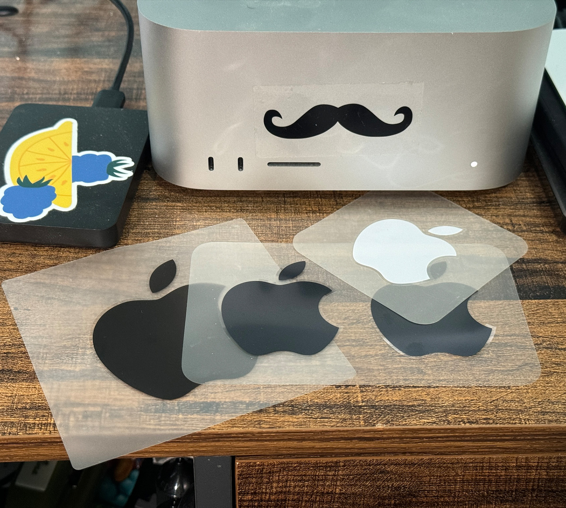 A picture of Apple stickers on a desk in front of a Mac Studio.