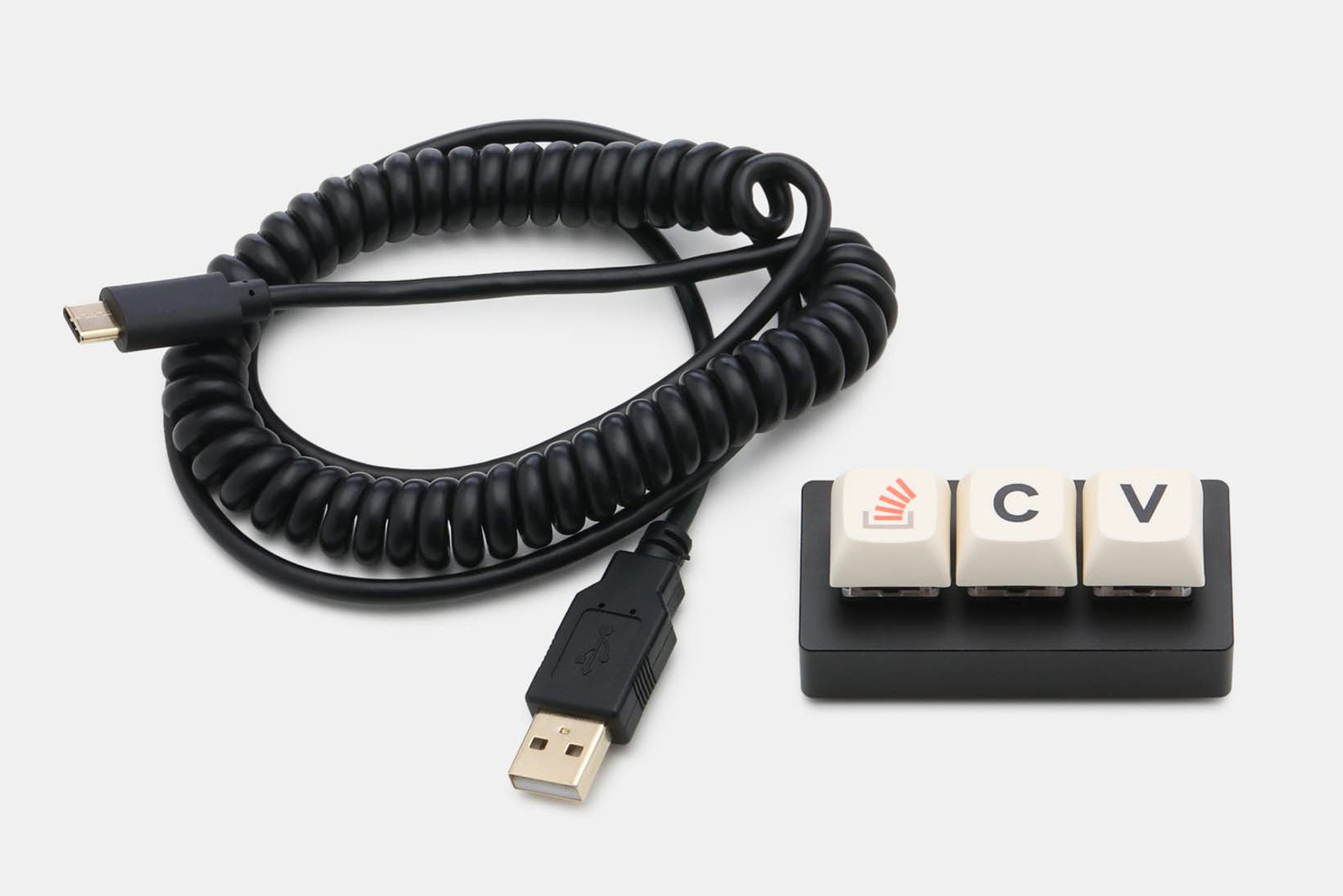 The Key laid horizontally on a white surface next to a black cord.