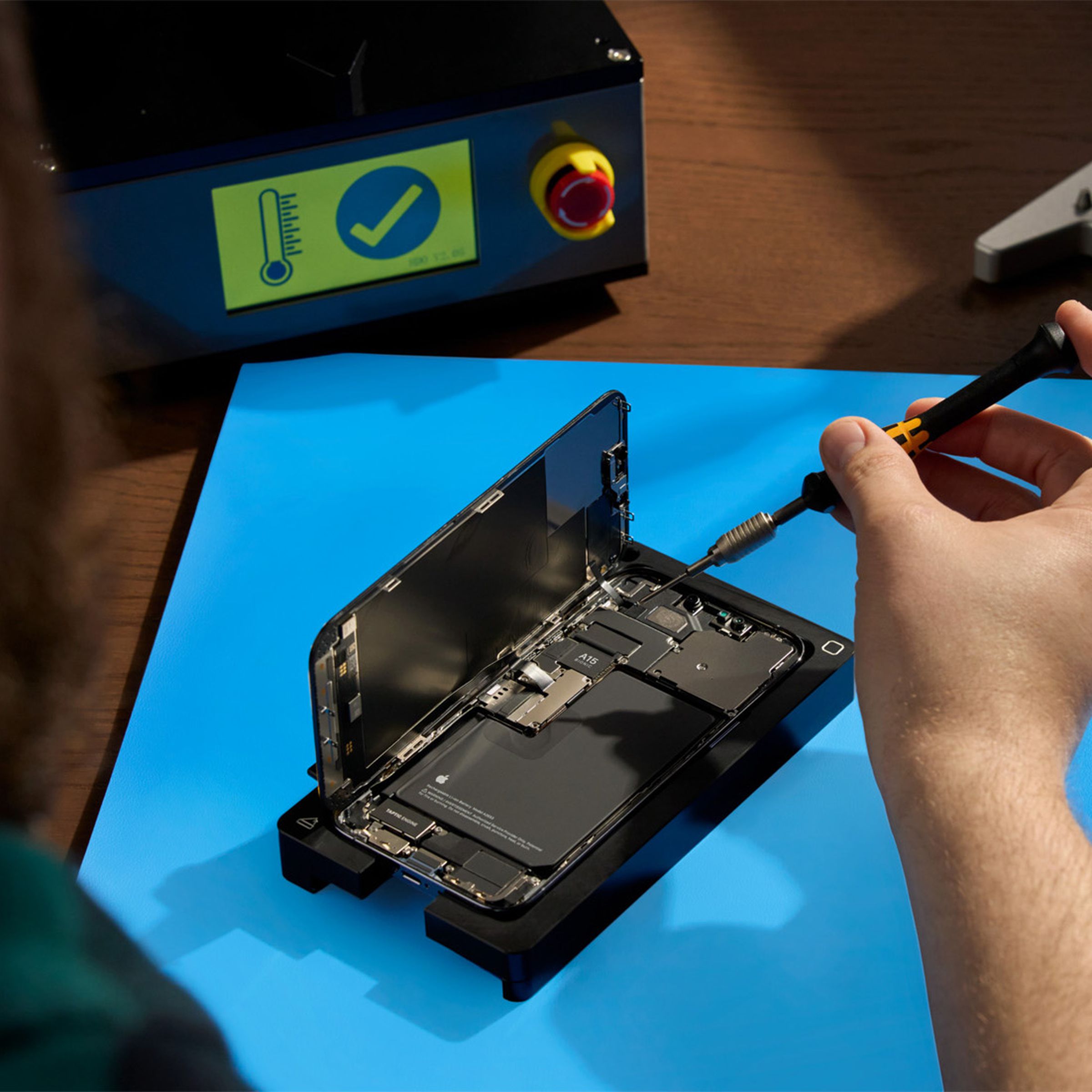 A person repairing a smartphone on a desk.