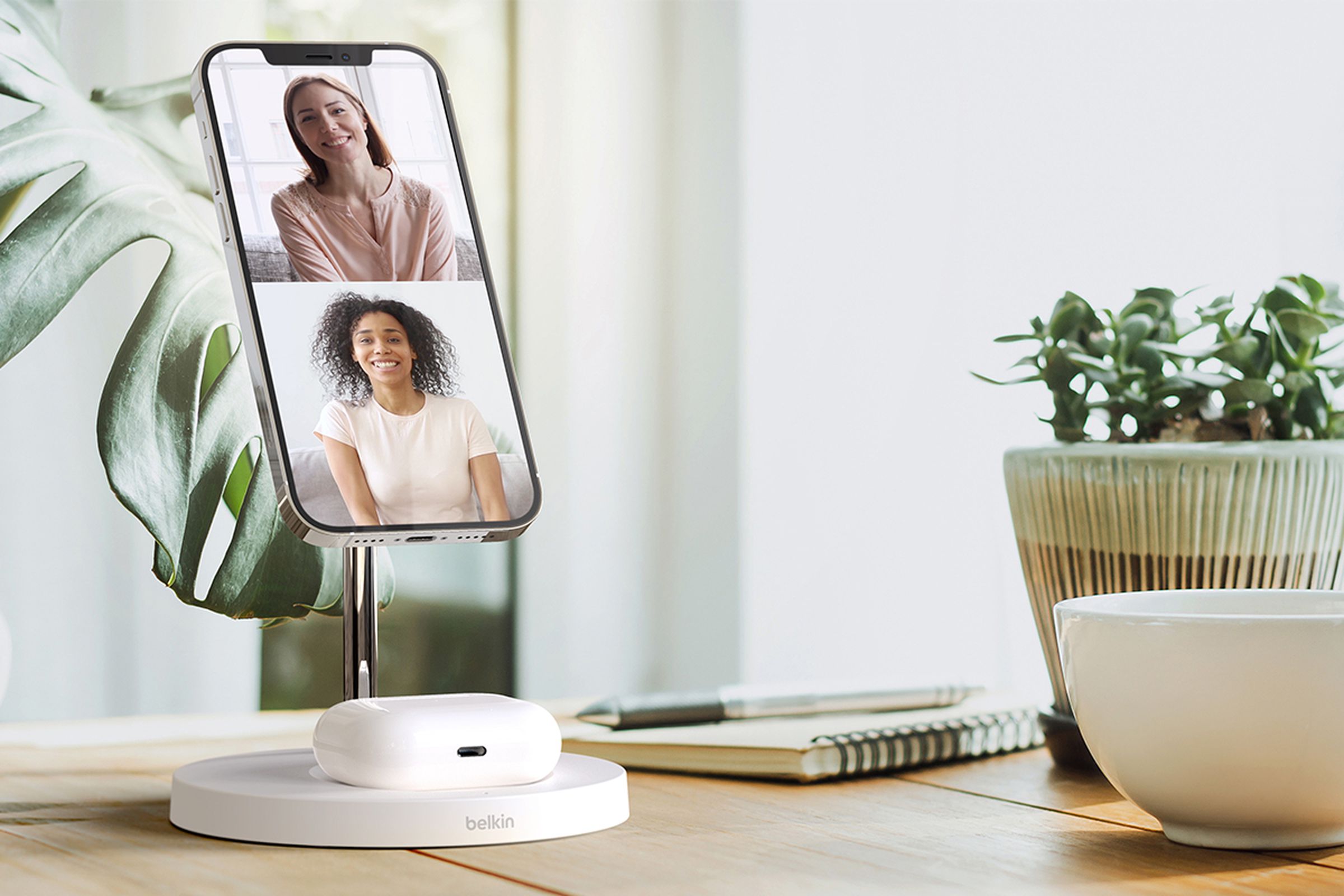 Belkin’s BoostCharge Pro MagSafe 2-in-1 Wireless Charger stand propping up a phone on a desk during a video call.