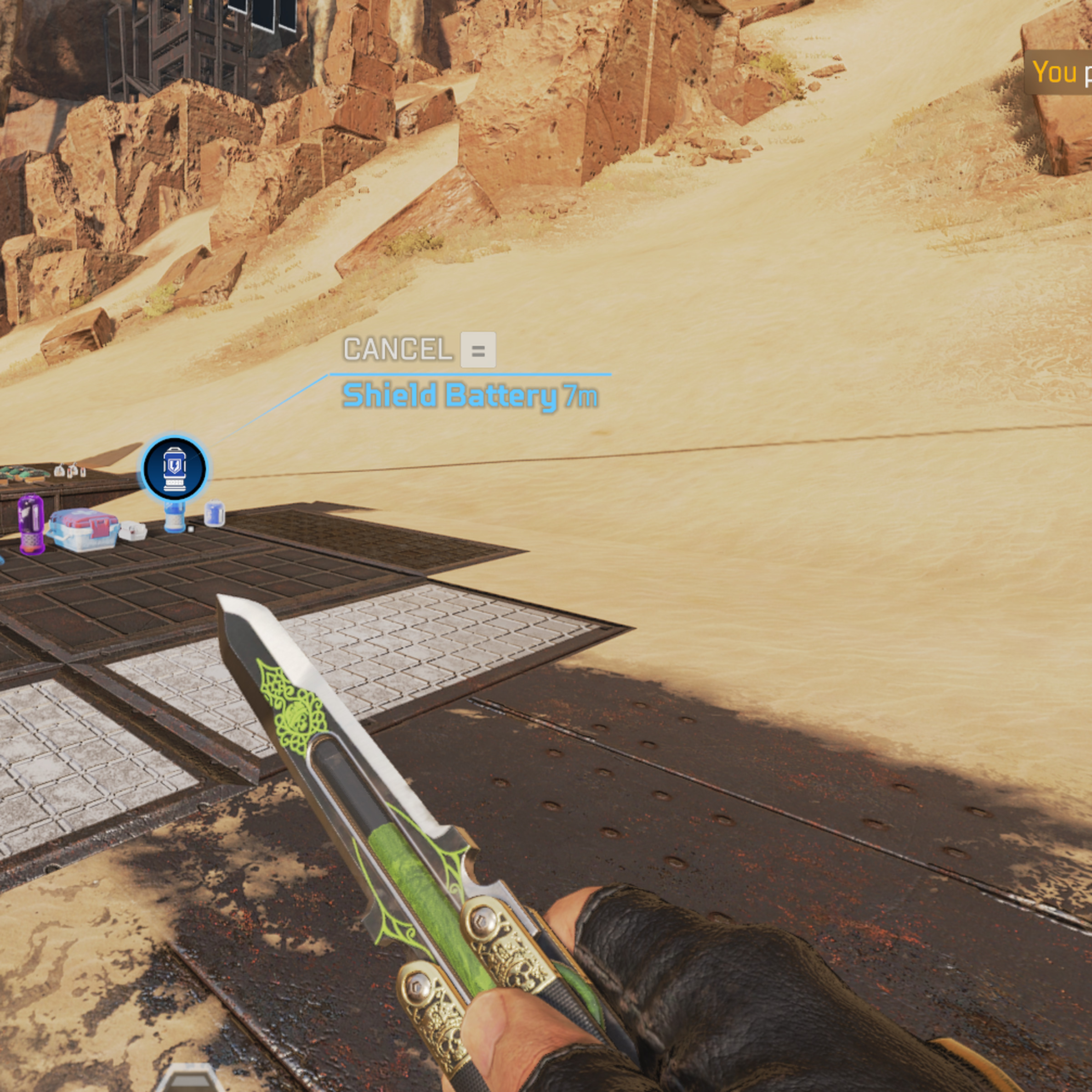 Screenshot of Apex Legends, showing a dessert landscape and a hand holding a knife, with text in the upper right corner that says “you pinged shield battery.”