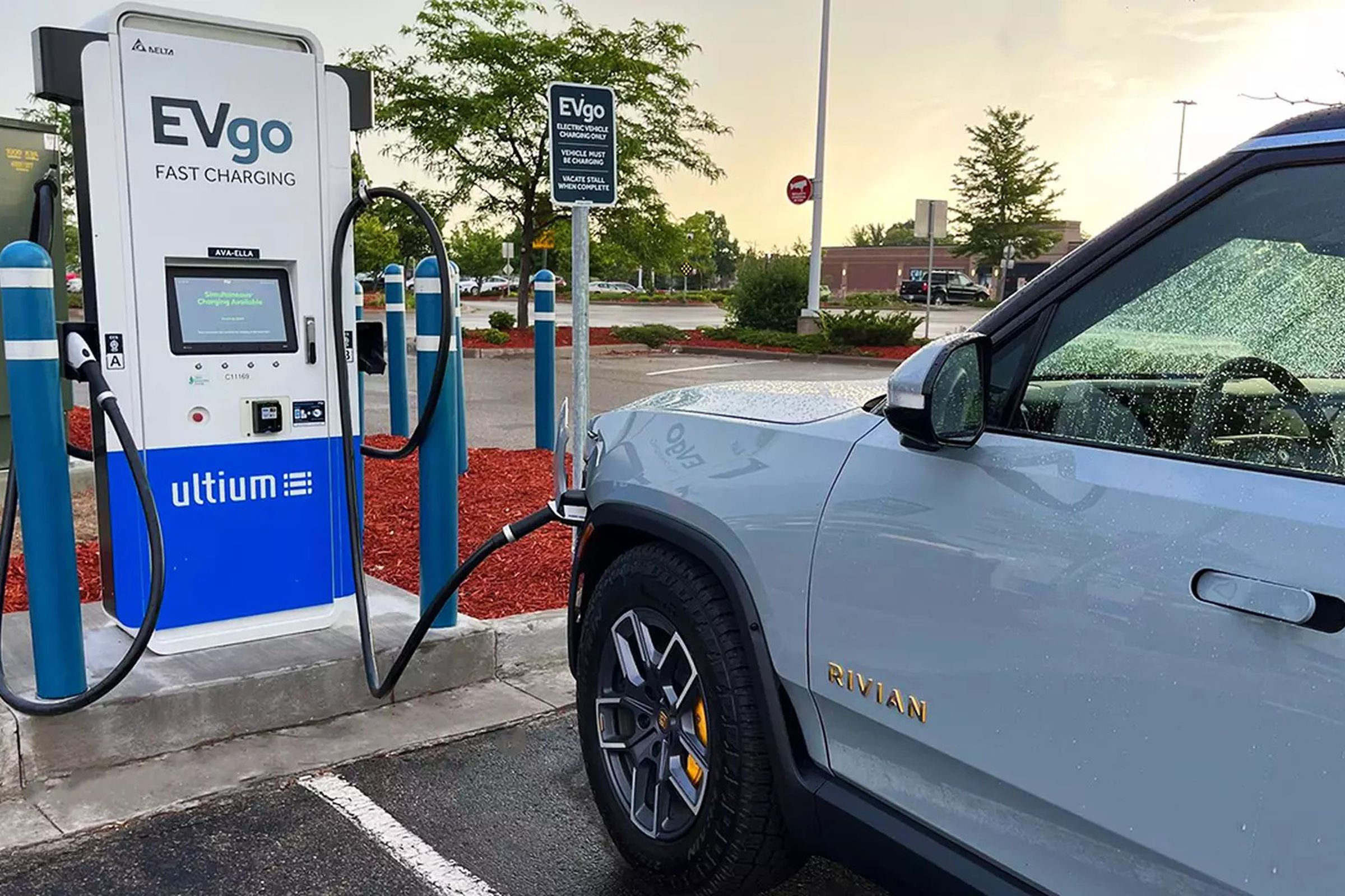 Blue Rivian truck plugged into EVgo dc fast charging station in retail parking lot
