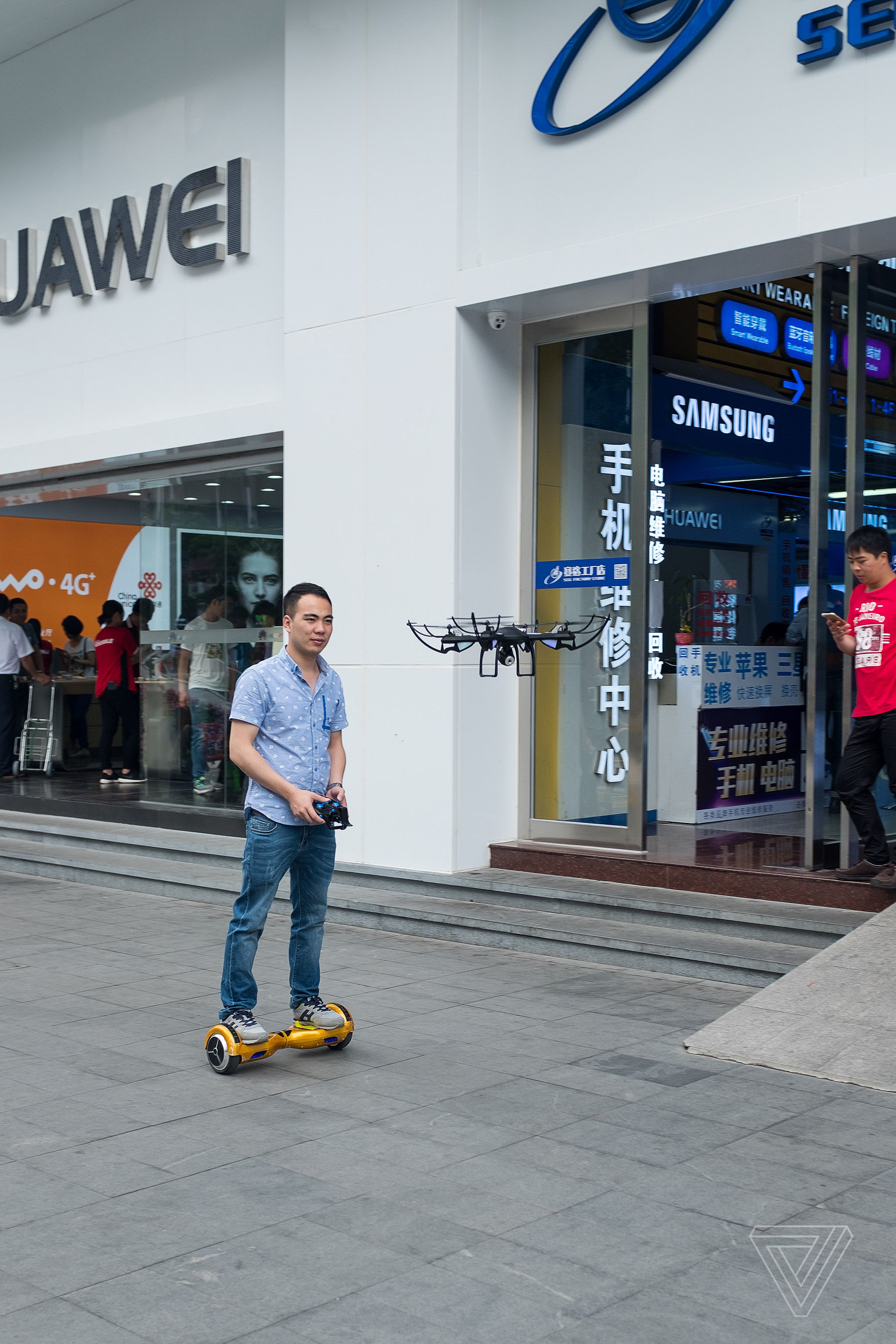 A man demonstrates a hoverboard and a drone outside of a shop in Shenzhen.
