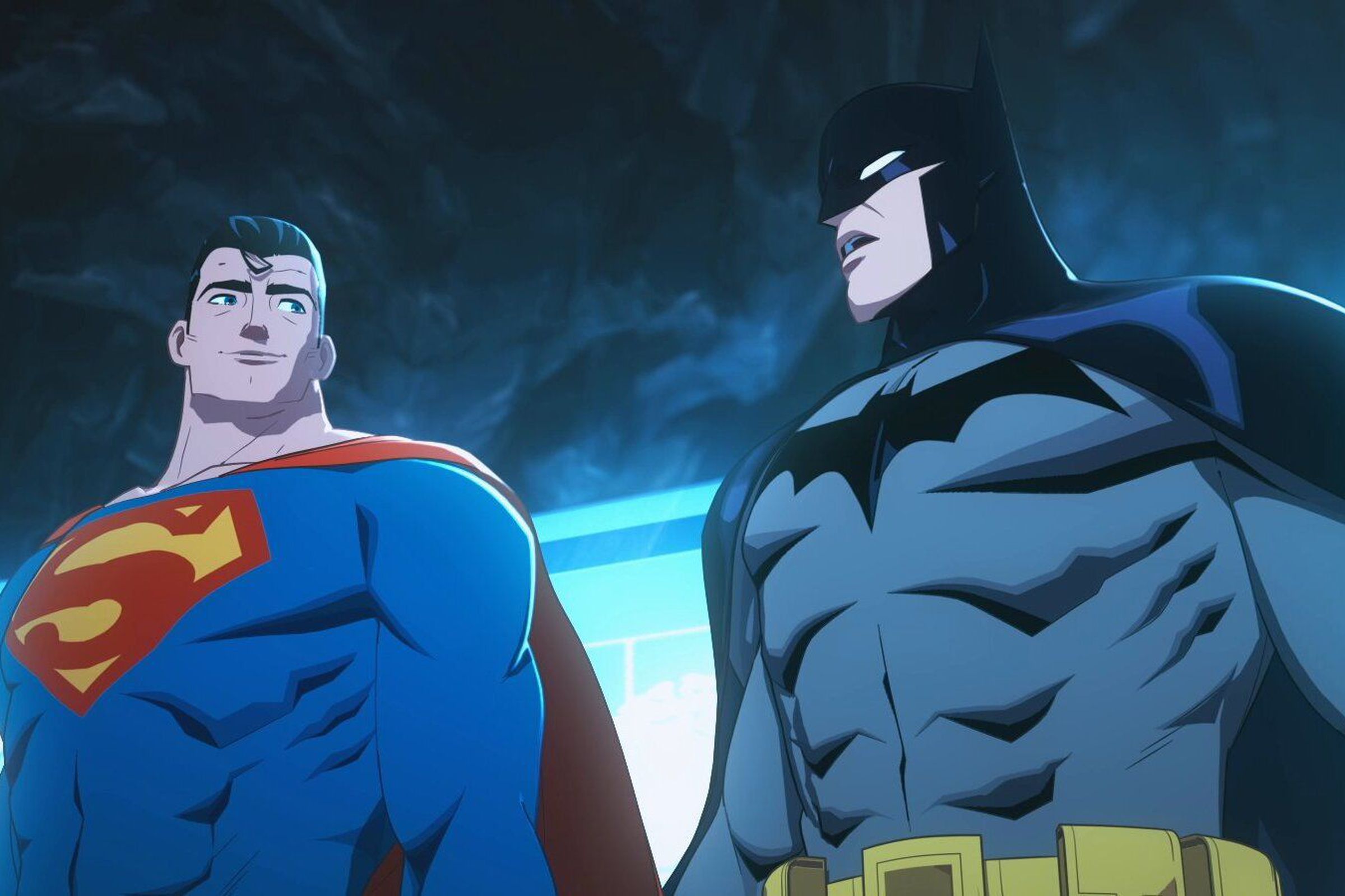 Superman and Batman standing in the Batcave in front of the Batcomputer, which is lighting them both from the back.