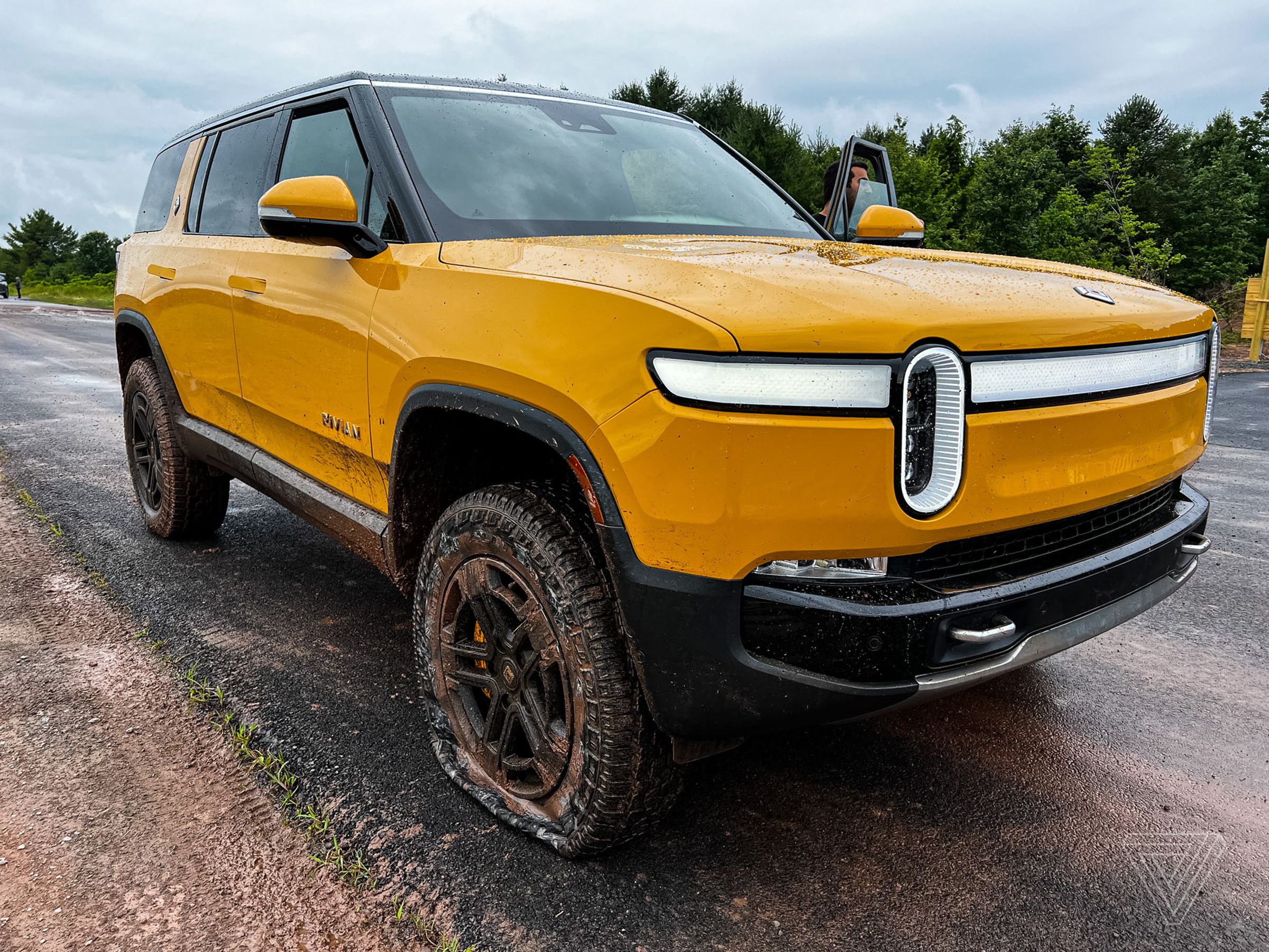 A yellow Rivian R1S with a flat front tire