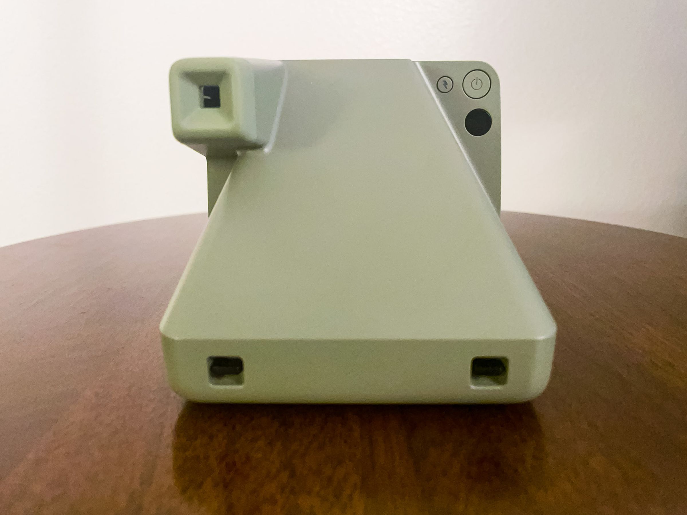 The back of the green second-gen Polaroid Now Plus resting on a table with its viewfinder.