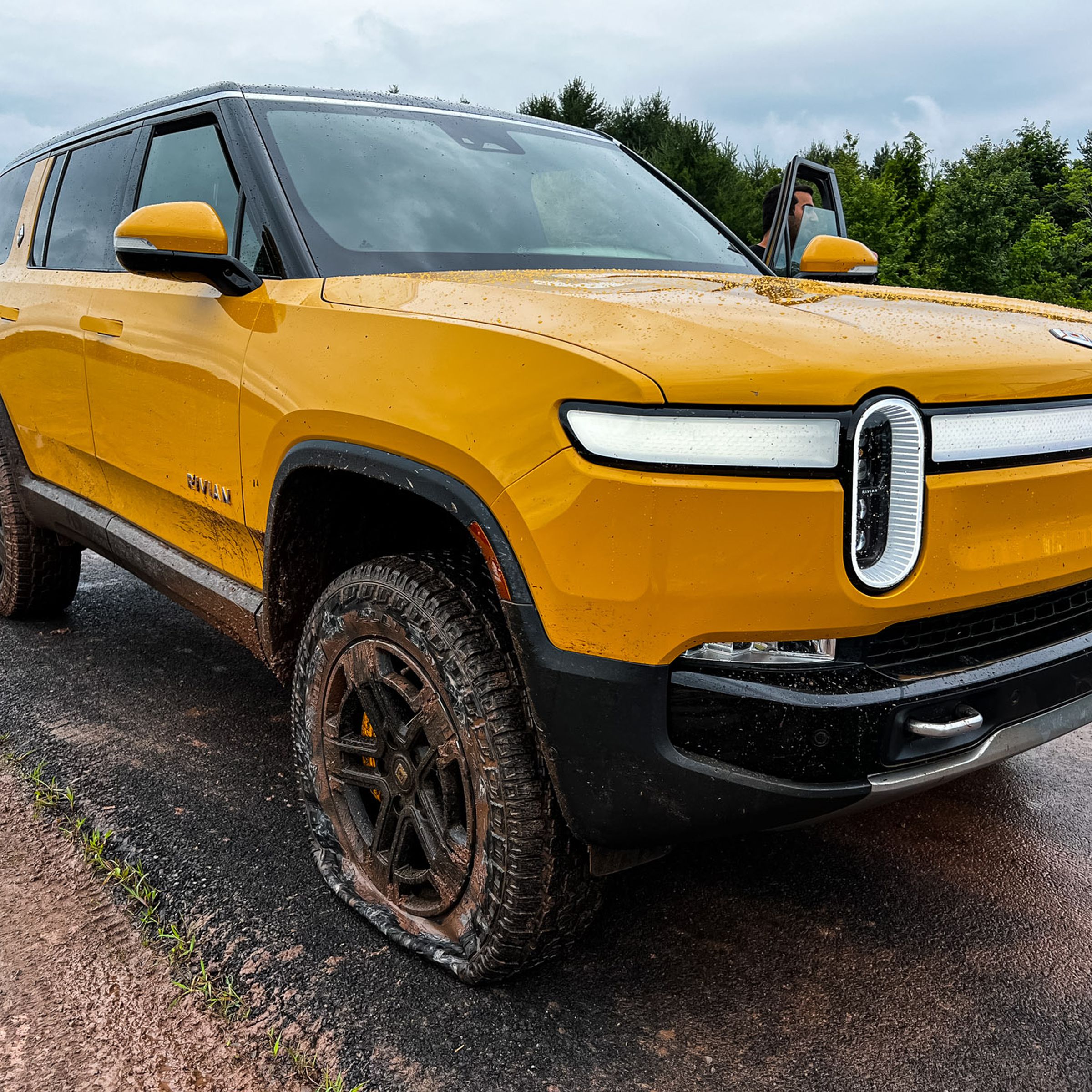 A yellow Rivian R1S with a flat front tire