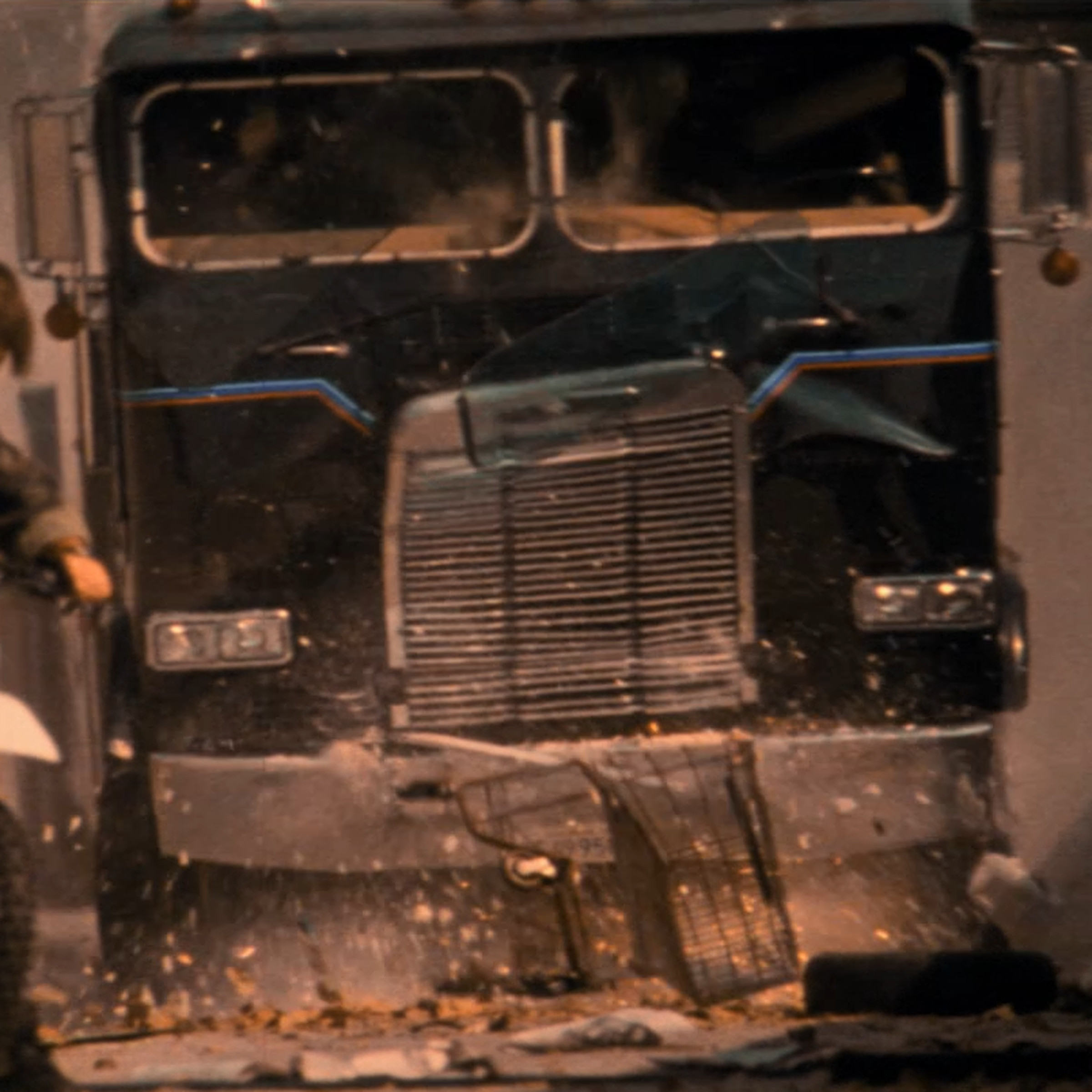A screenshot from Terminator 2 showing a person on a dirtbike in the foreground and a flat-nosed semi truck in the background, approaching him.