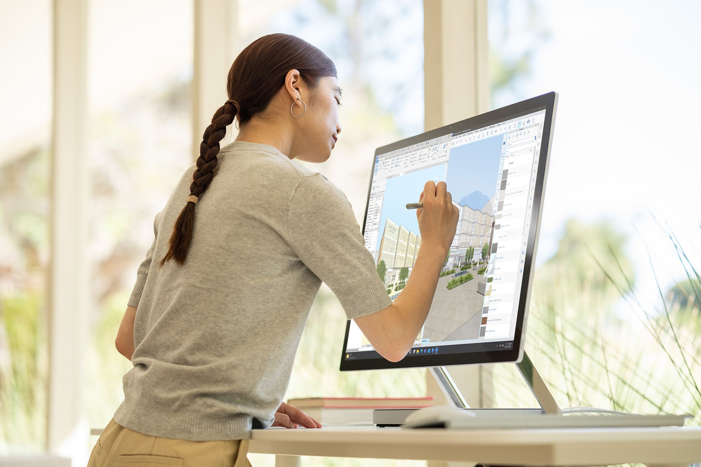A user draws with a stylus on the Surface Studio 2 Plus at a standig desk.