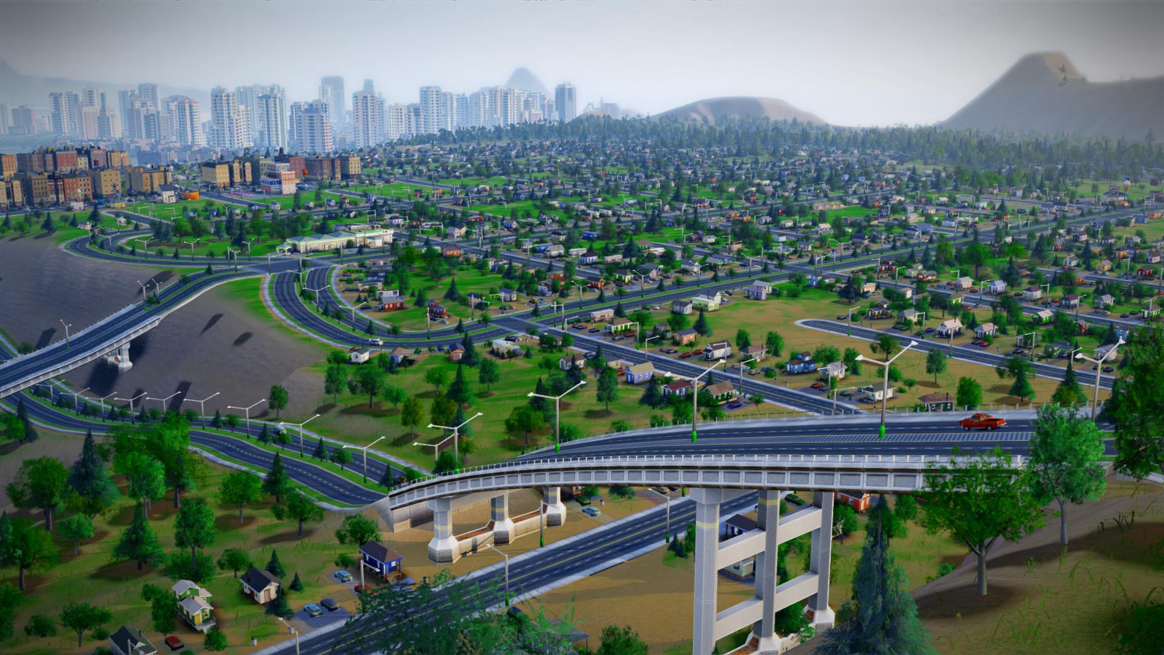 A highway running over a suburban landscape with a city and mountains in the background.
