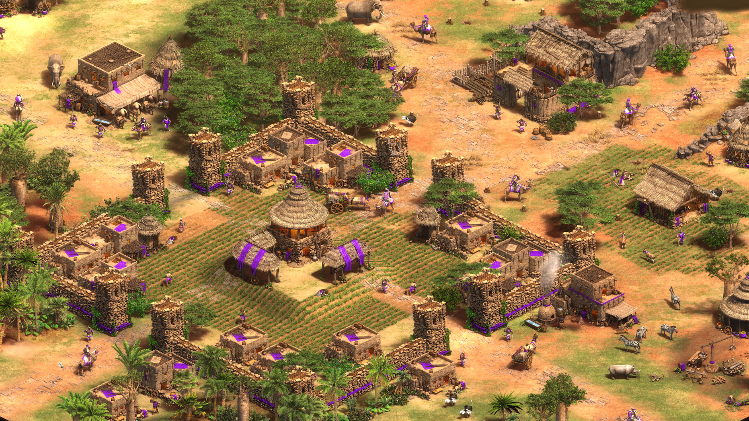 Captura de pantalla de Age of Empires: II Definitive Edition que muestra una pequeña ciudad bordeada de estandartes morados