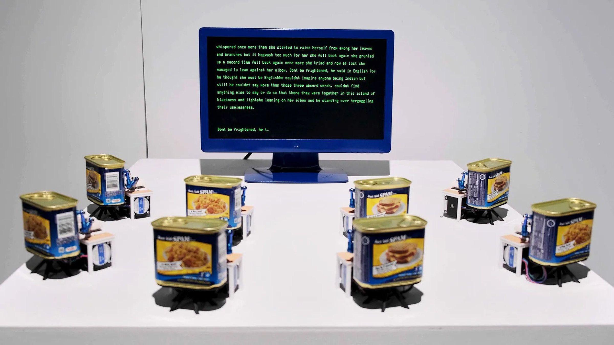 Eight tins of Spam converted into typing robots surrounding a display.