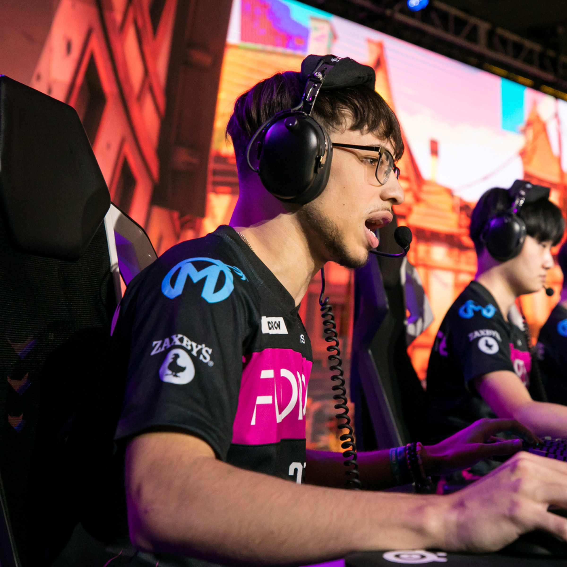 Photo from the Overwatch League playoffs featuring Florida Mayhem player Isaiah “Hydron” Rodriguez in a black and pink Mayhem jersey wearing heavy headphones yelling at a computer screen while playing Overwatch 2