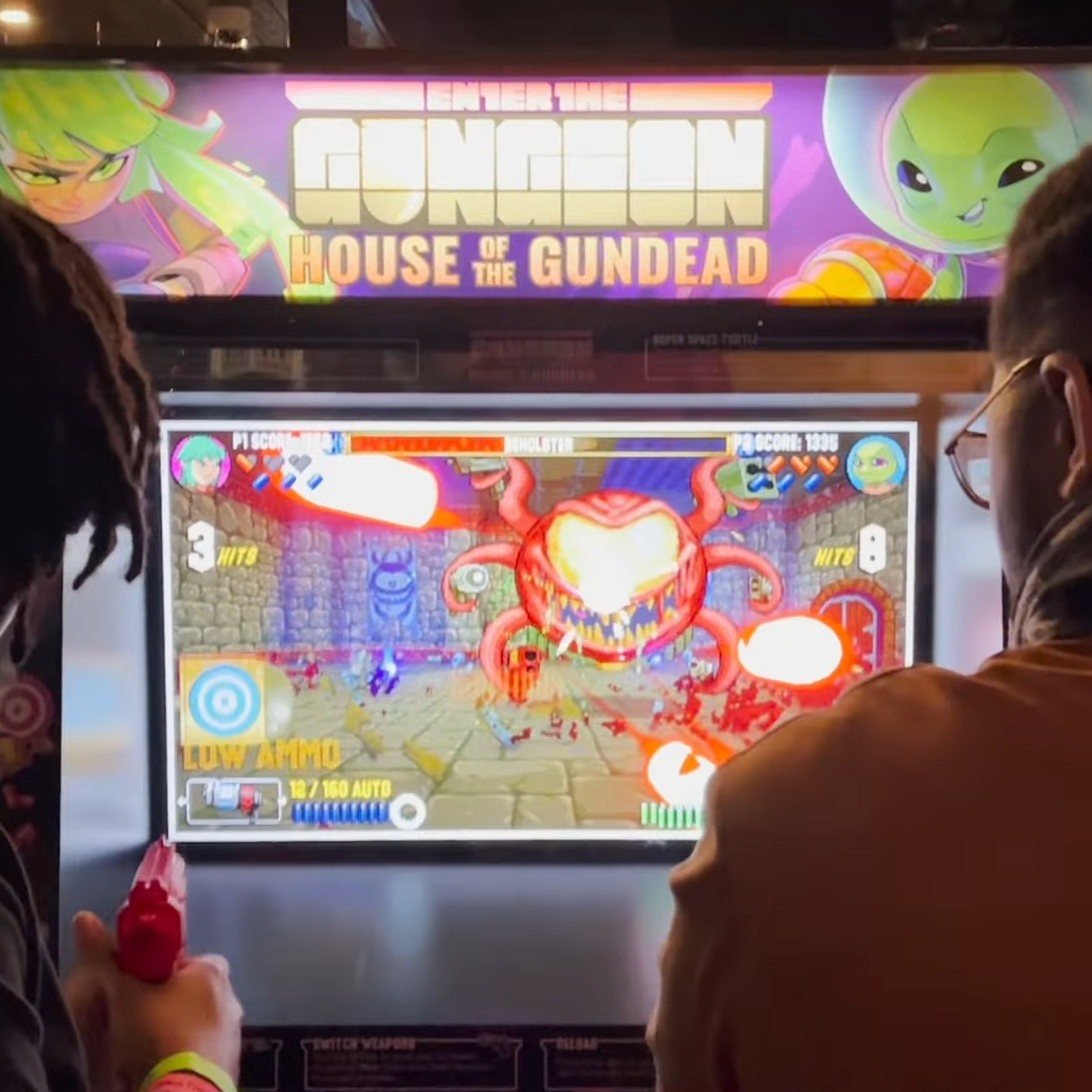Two people playing the House of the Gundead arcade machine.