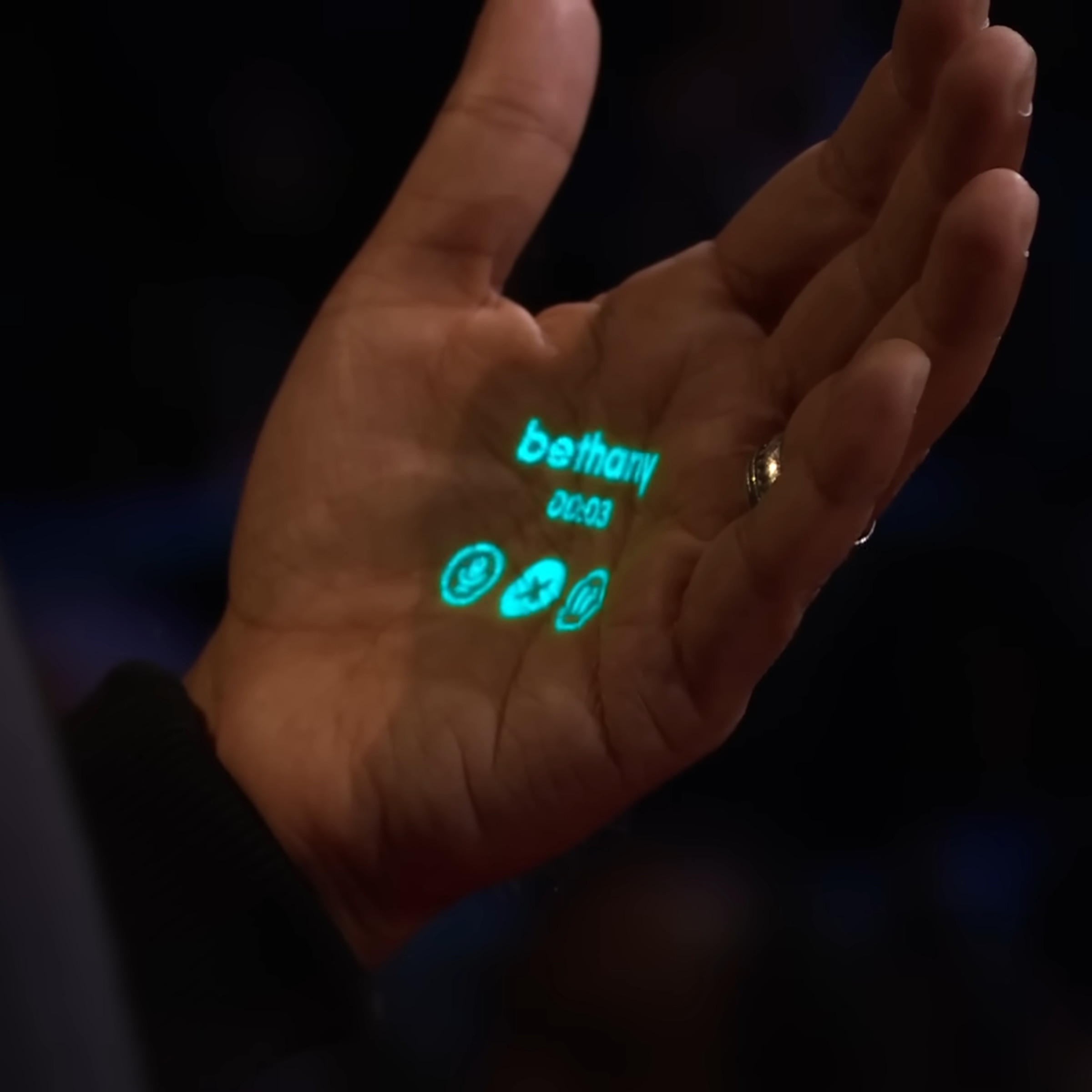 A photo from Imran Chaudhri’s TED talk about the Humane Ai Pin. The device projects details of a phone call onto his hand.