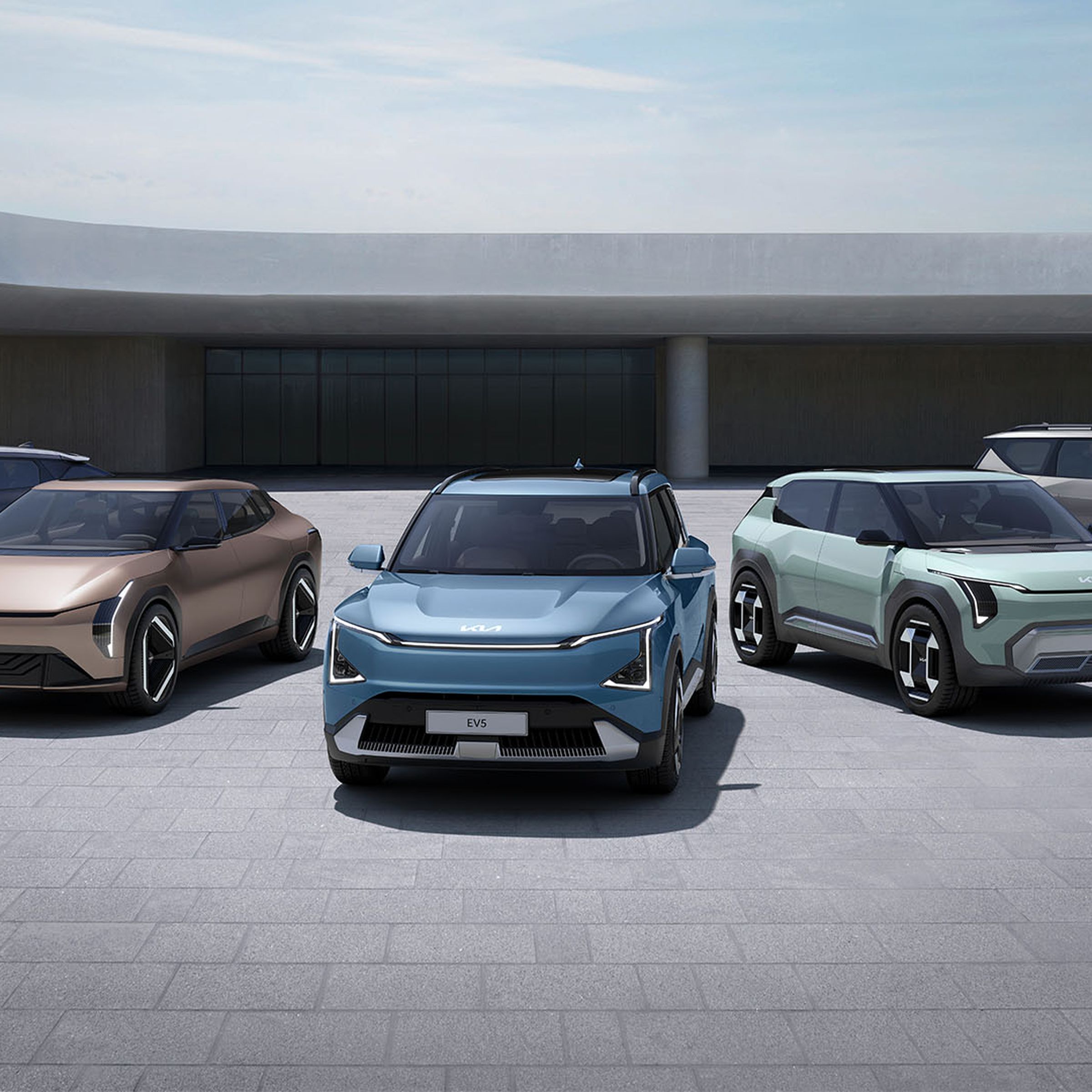 five electric kia vehicles fanned out in a modern architecture area with stone brick flooring