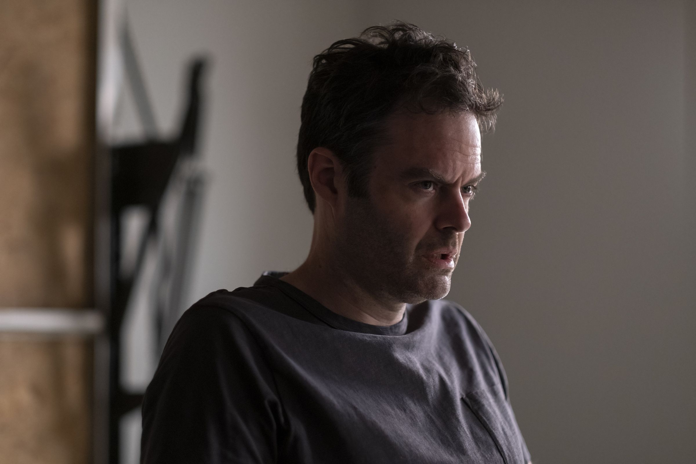 Screenshot from Max show Barry featuring Bill Hader as the character Barry a caucasian man with a grim expression wearing a fadded blue t-shirt.