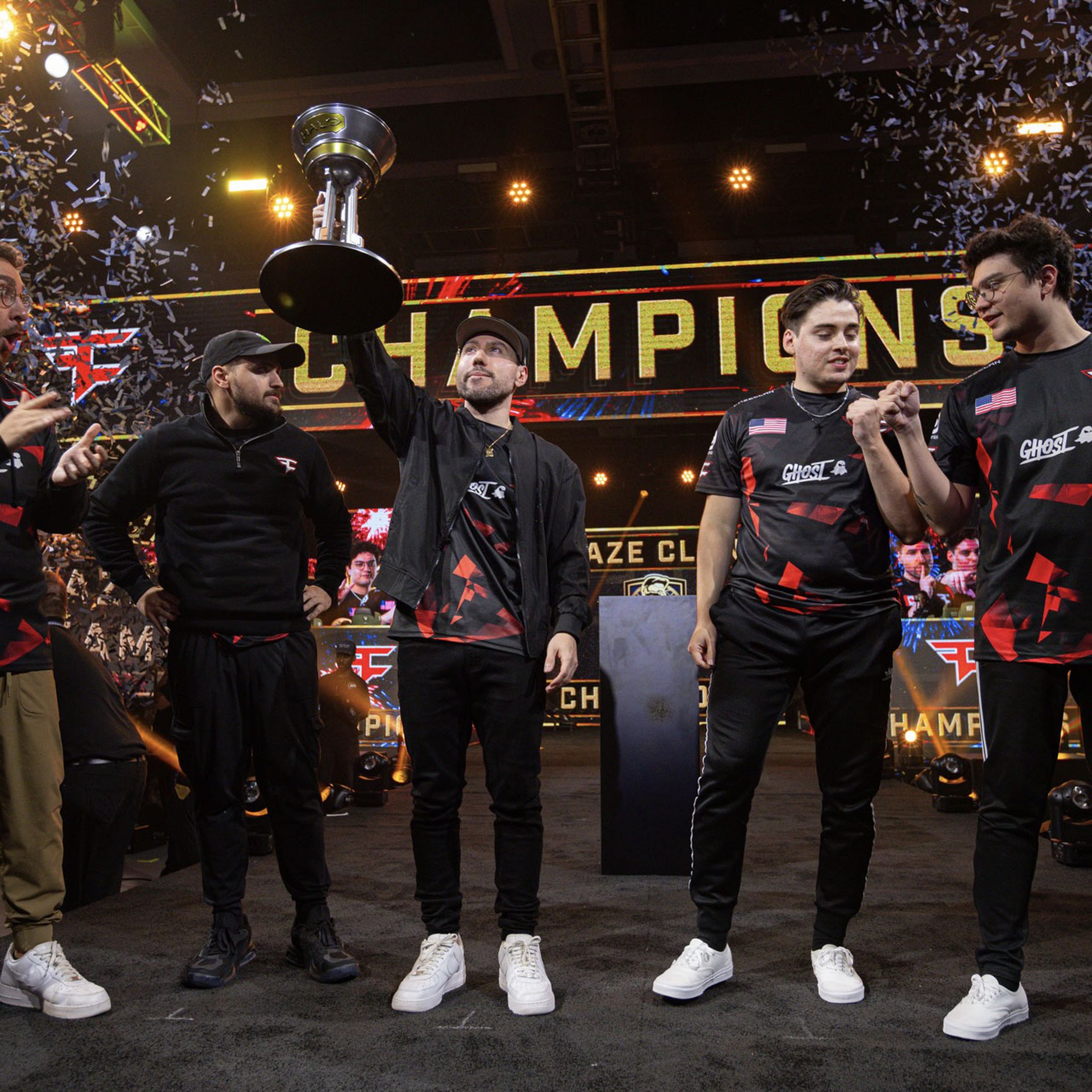 Five Faze Clan participants in celebration with one holding up trophy as confetti drops and champions banner displays above