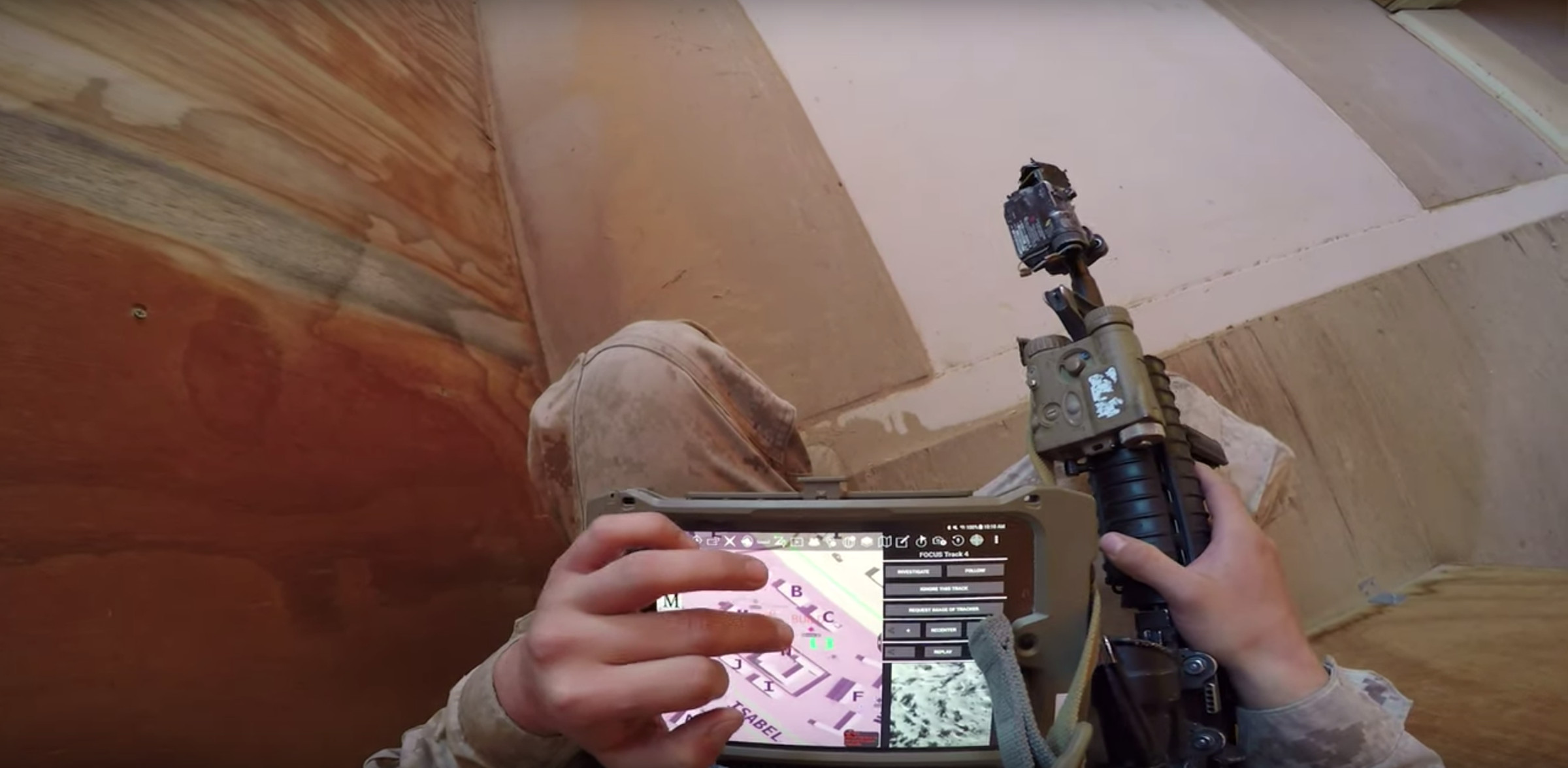 A first-person view of a Marine looking at their tablet in a room. 