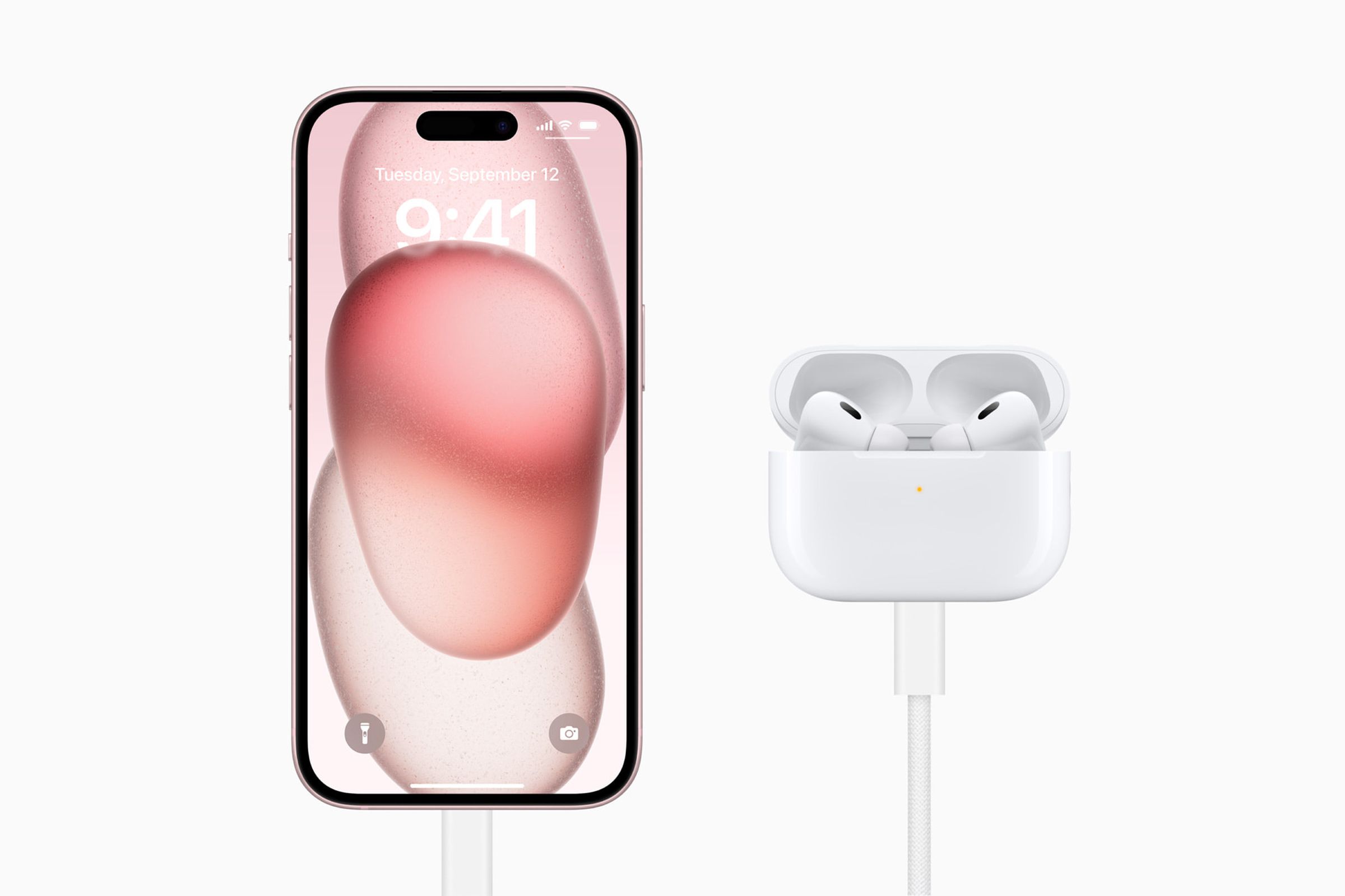 An iPhone 15 charging a set of AirPods Pro in their case.