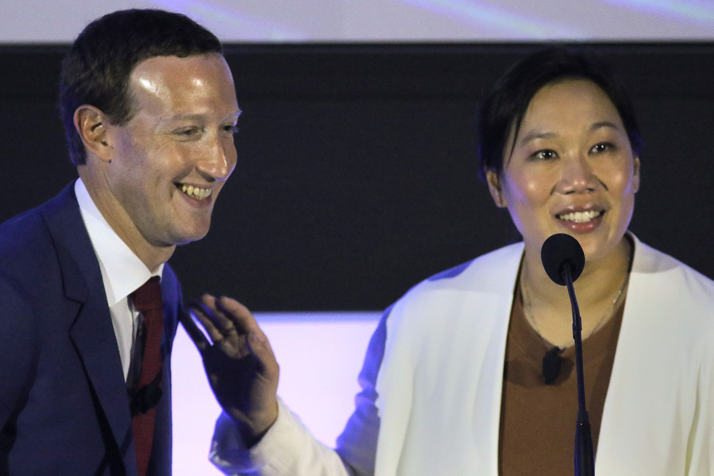 Mark Zuckerberg and Priscilla Chan stand next to each other smiling