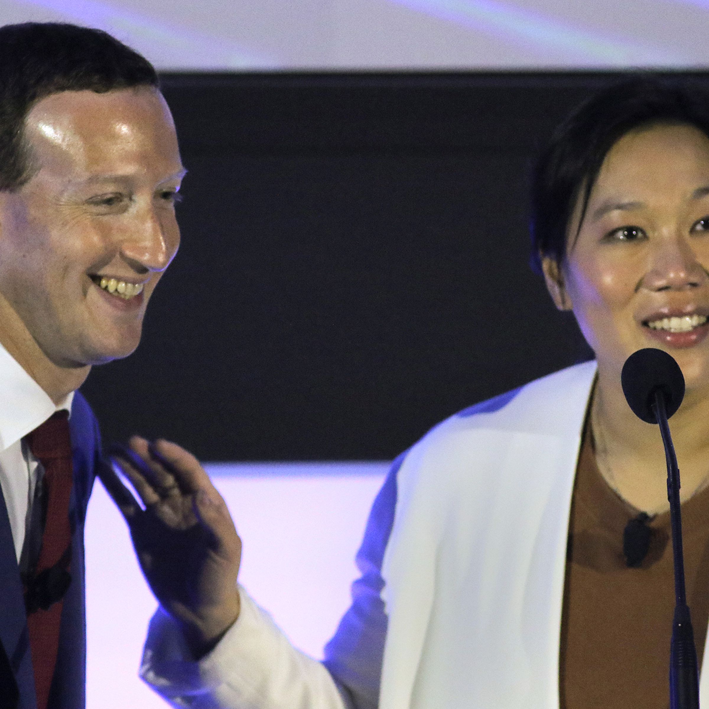 Mark Zuckerberg and Priscilla Chan stand next to each other smiling