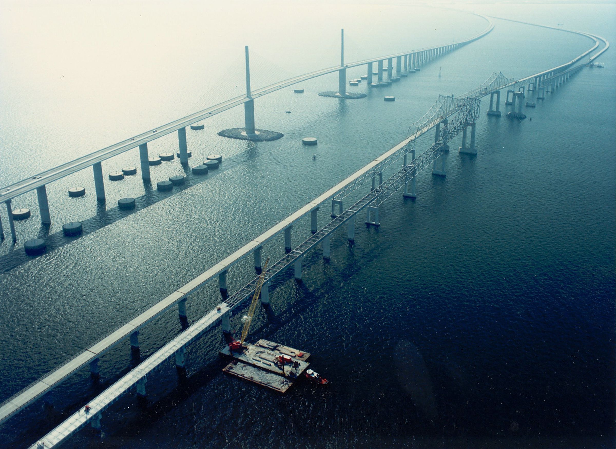 The old Sunshine Skyway Bridge (right) next to the new one (left), with concrete dolphins surrounding its piers.