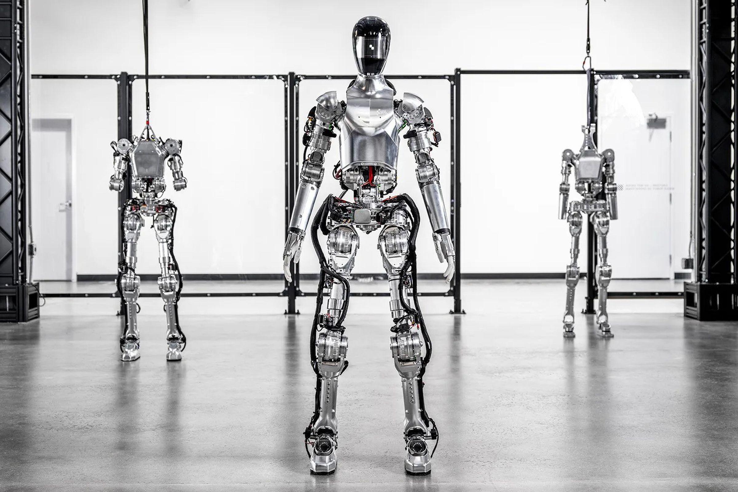Three of Figure’s prototype humanoid robots displayed in a factory setting.
