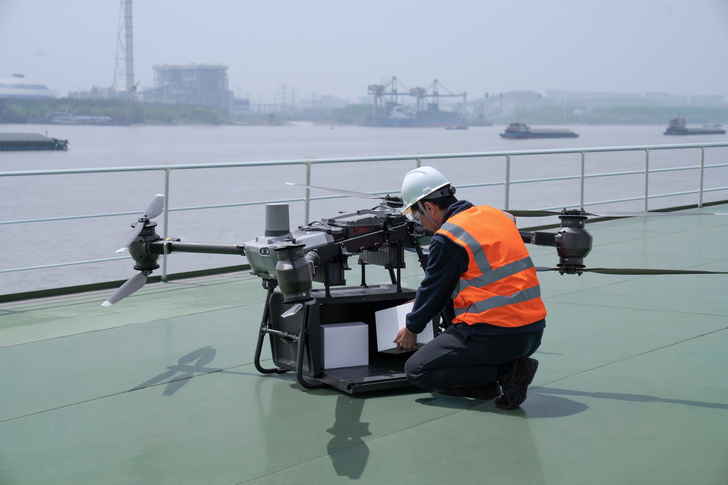A photo of DJI’s FlyCart 30 drone. A person is next to it loading goods into a box.