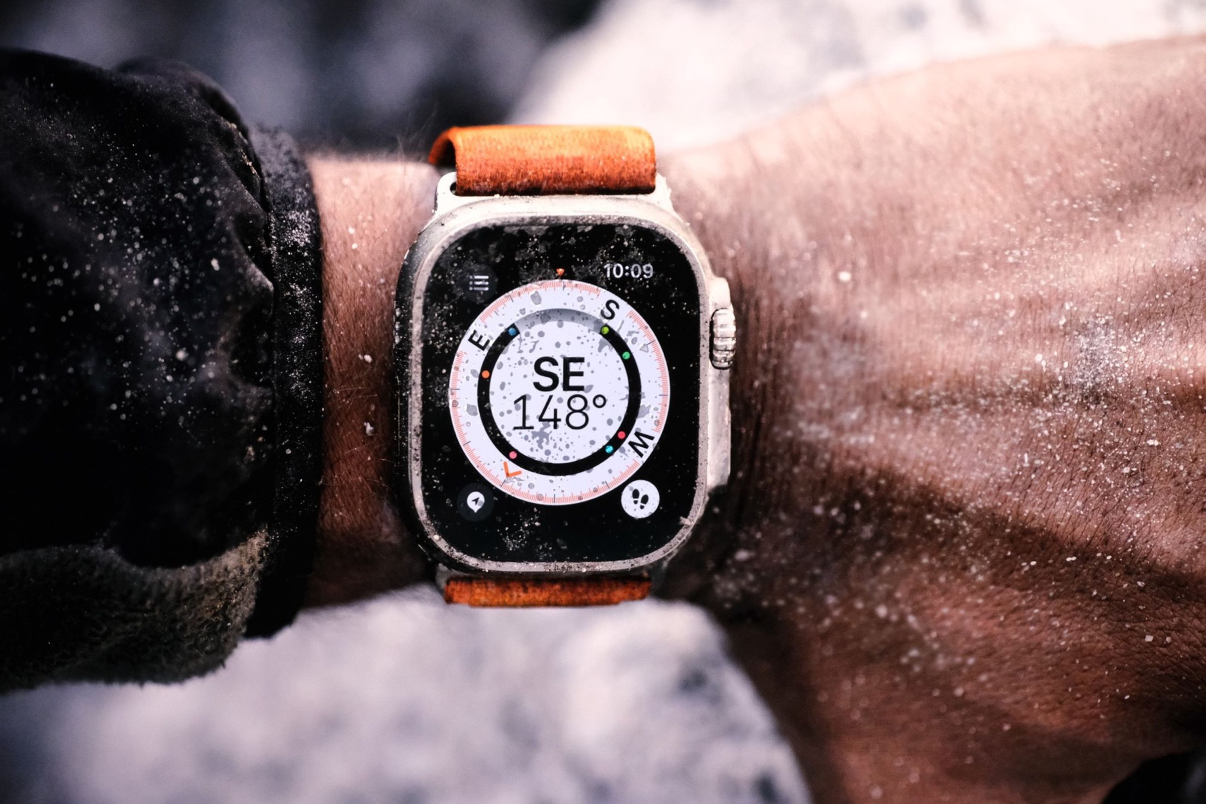 Photo of a wrist covered in dirt, with the Apple Watch Ultra displaying a compass.