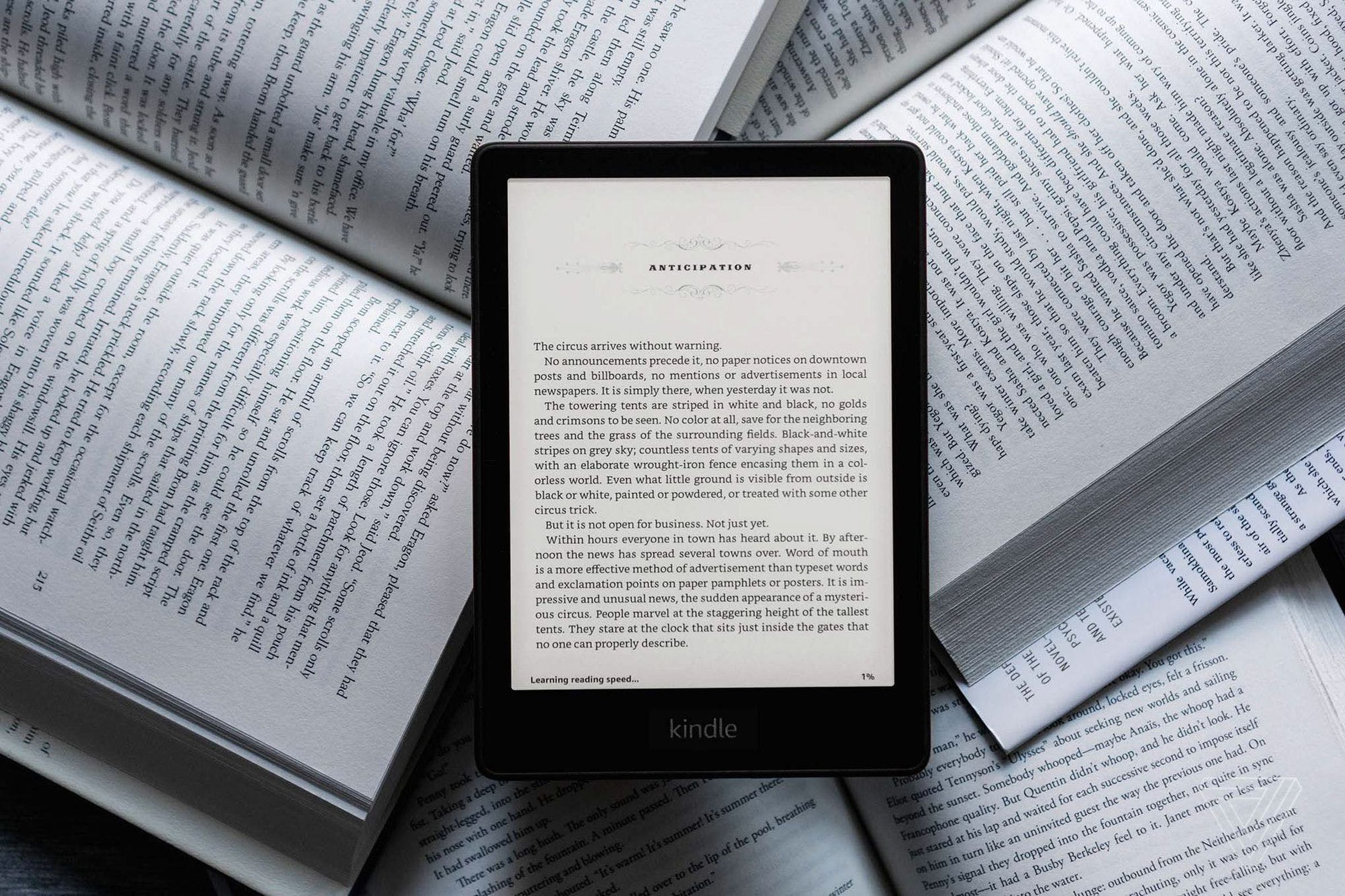 The Kindle Paperwhite e-reader turned with its display on while lying on top of open books.