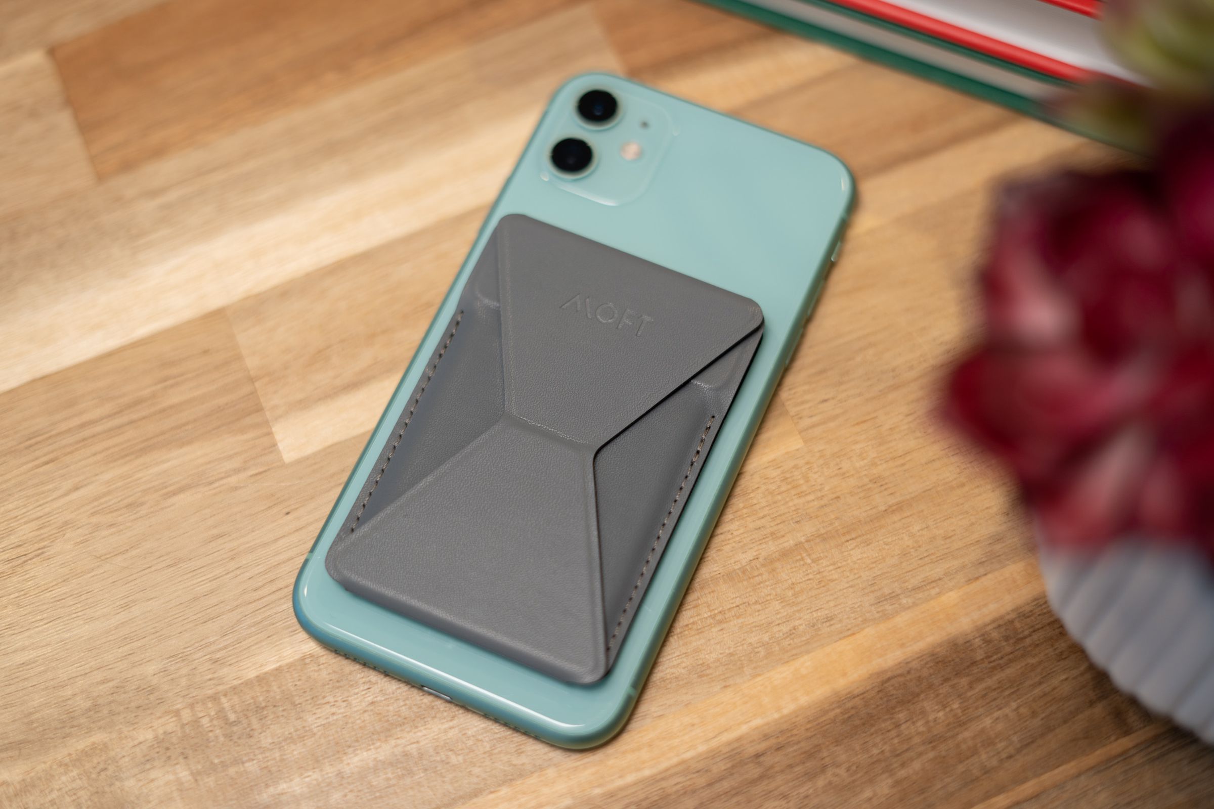 Grey Moft wallet on the back of a green iPhone 11 face down on a table.