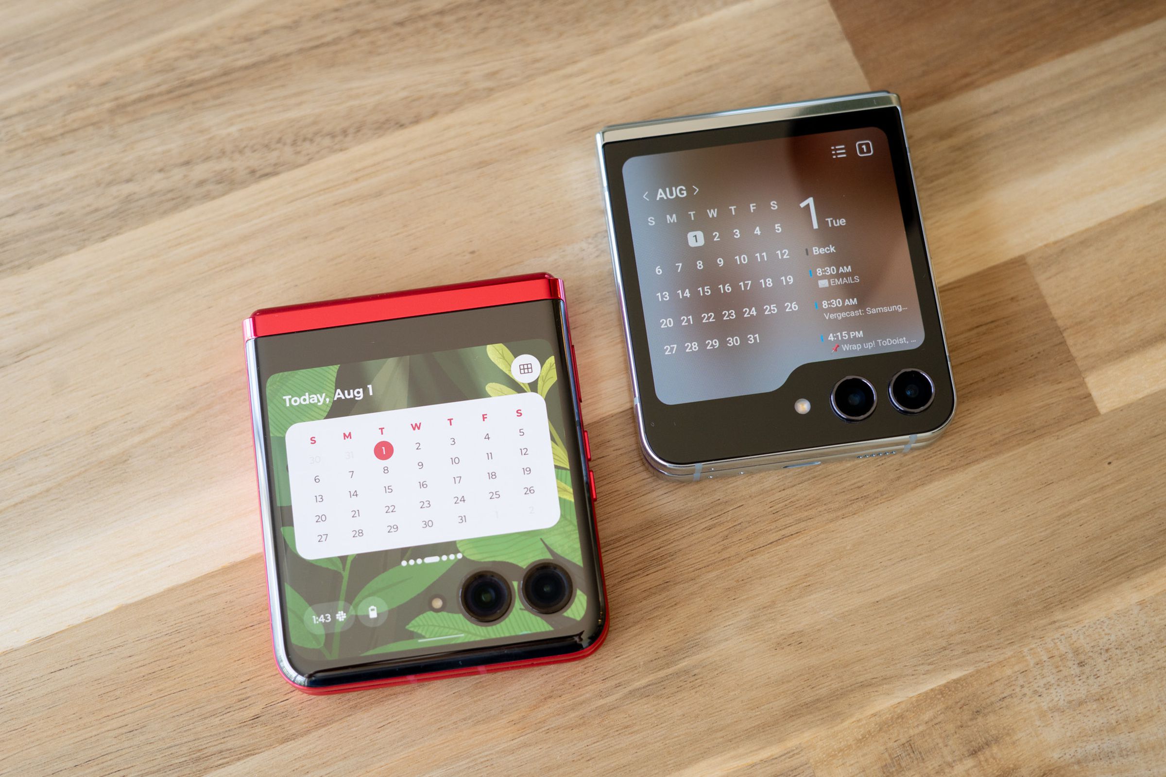 Motorola Razr and Galaxy Z Flip 5 sitting on a table showing calendar widgets on cover screen.