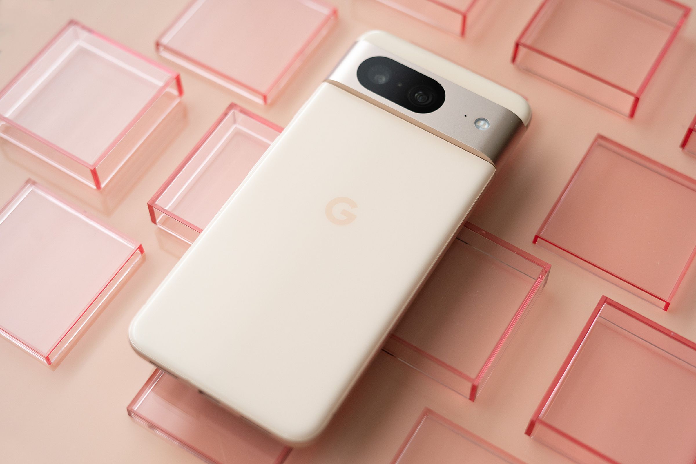 Google Pixel 8 in pink on a pink background with red transparent squares.
