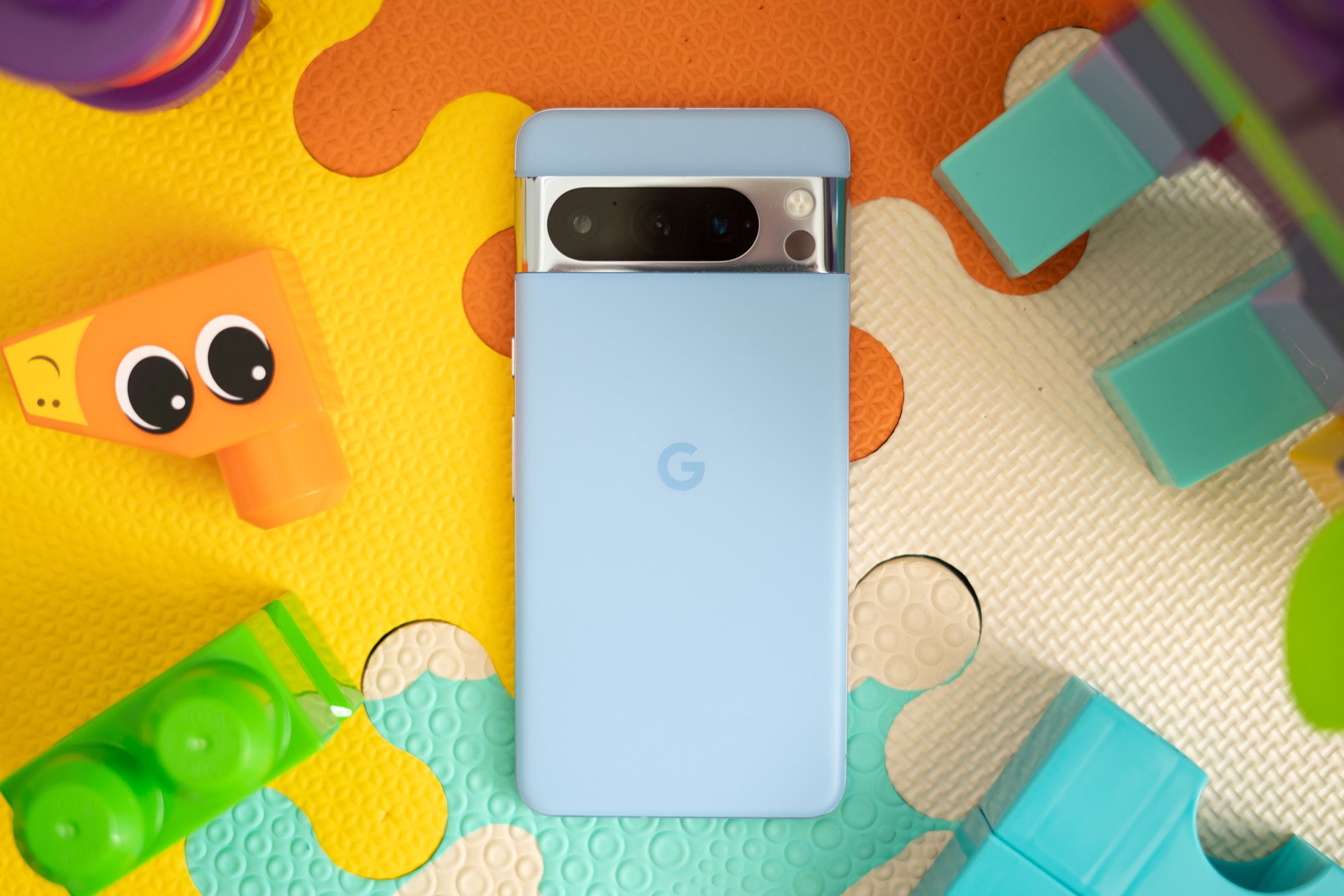 Photo of blue Google Pixel 8 Pro on a colorful play mat surrounded by building blocks