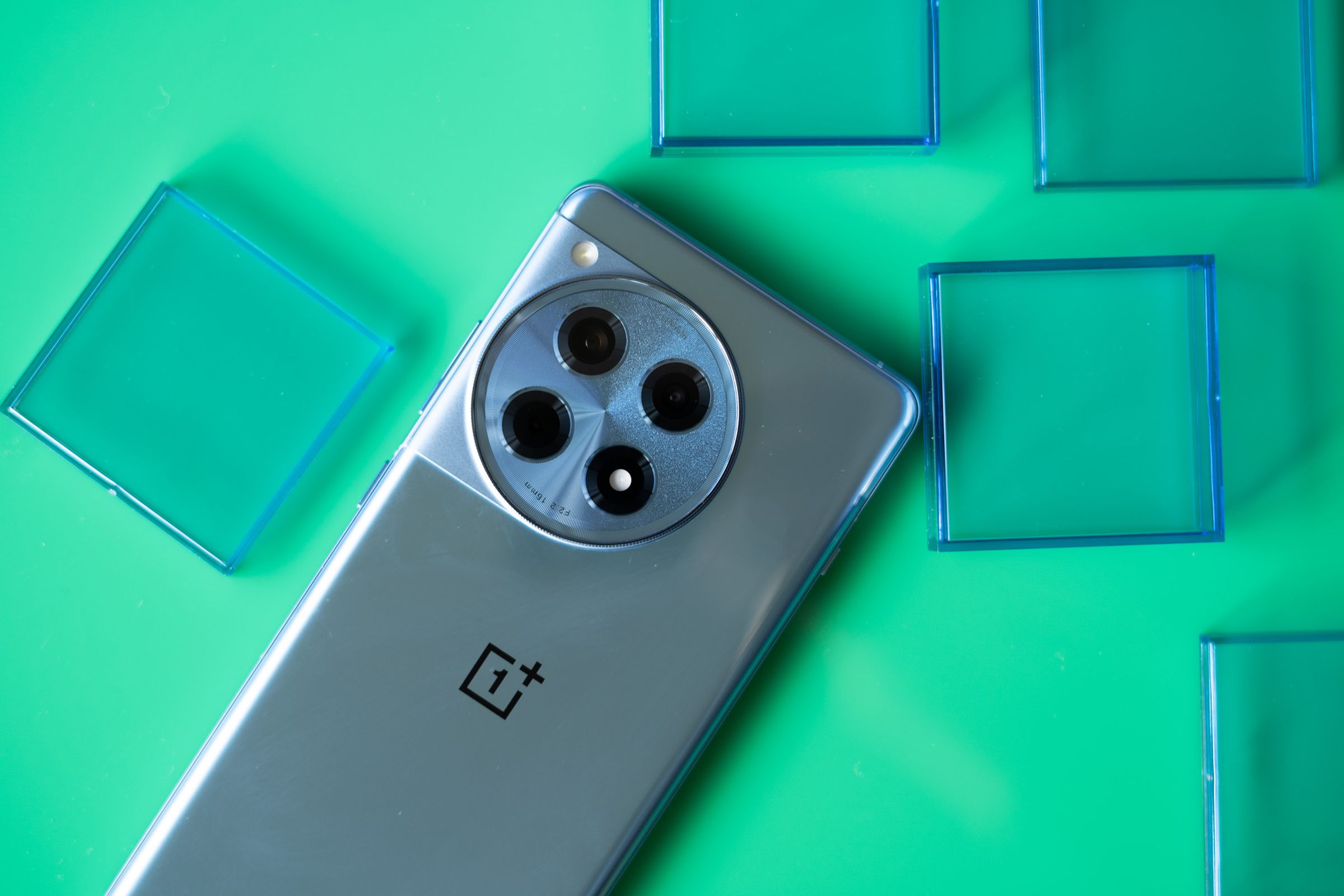OnePlus 12R on a green background with blue translucent squares.