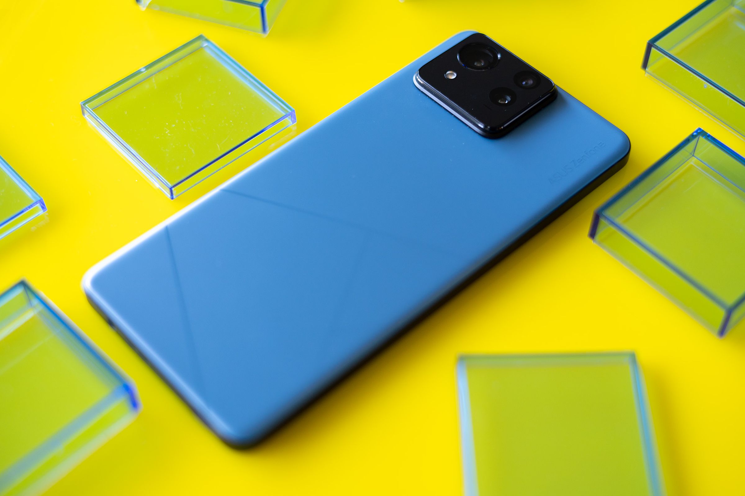 Asus Zenfone 11 Ultra on a yellow background surrounded by blue translucent squares.