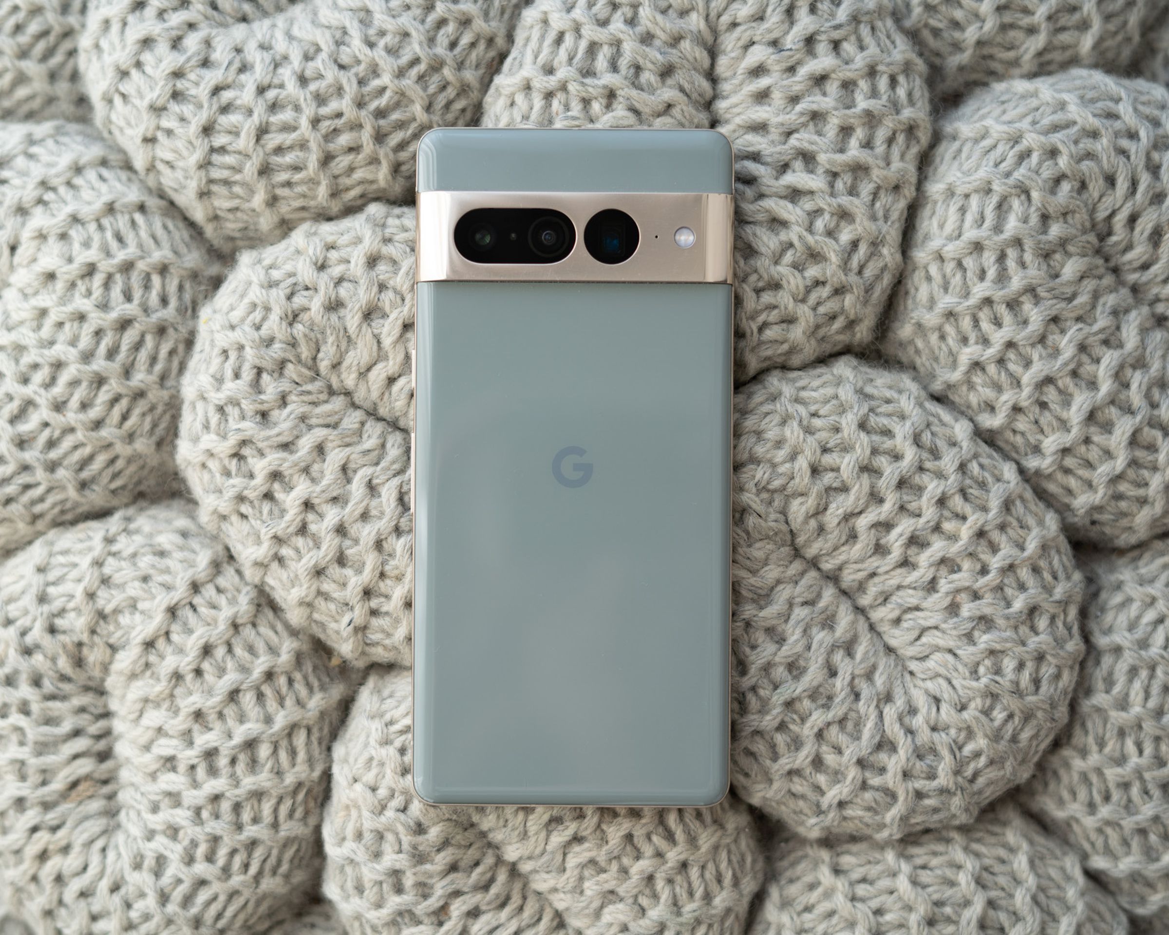 Google Pixel 7 Pro sitting with rear panel facing up on a grey knitted textured background.