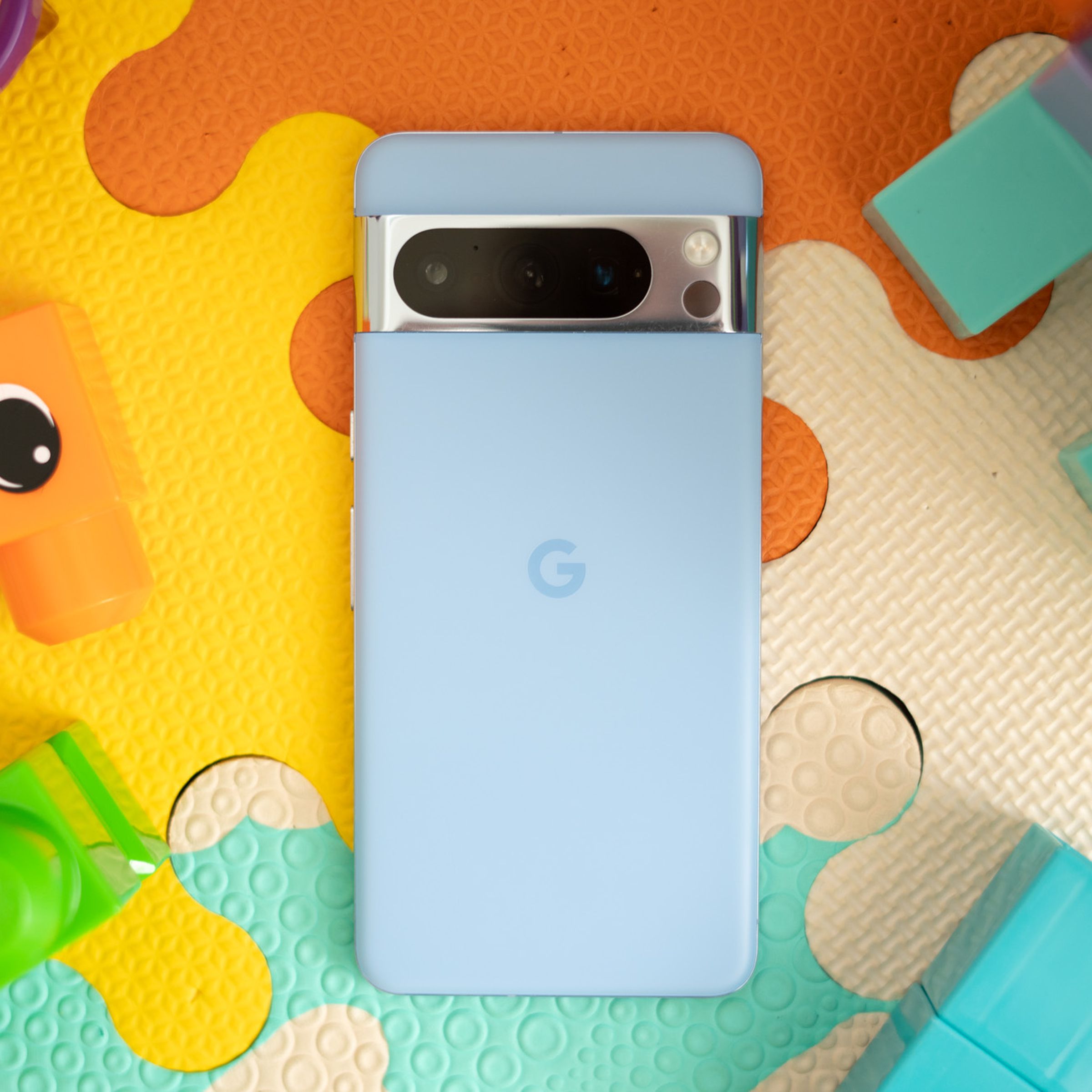 Photo of blue Google Pixel 8 Pro on a colorful play mat surrounded by building blocks