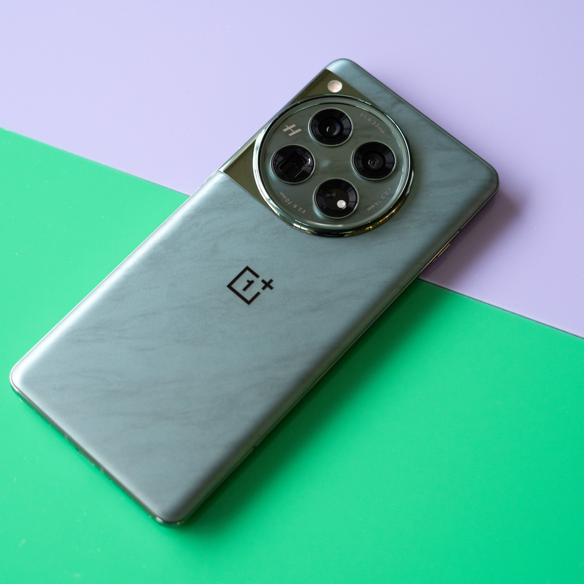 OnePlus 12 on a green and purple background showing back of the phone in marbled green color.