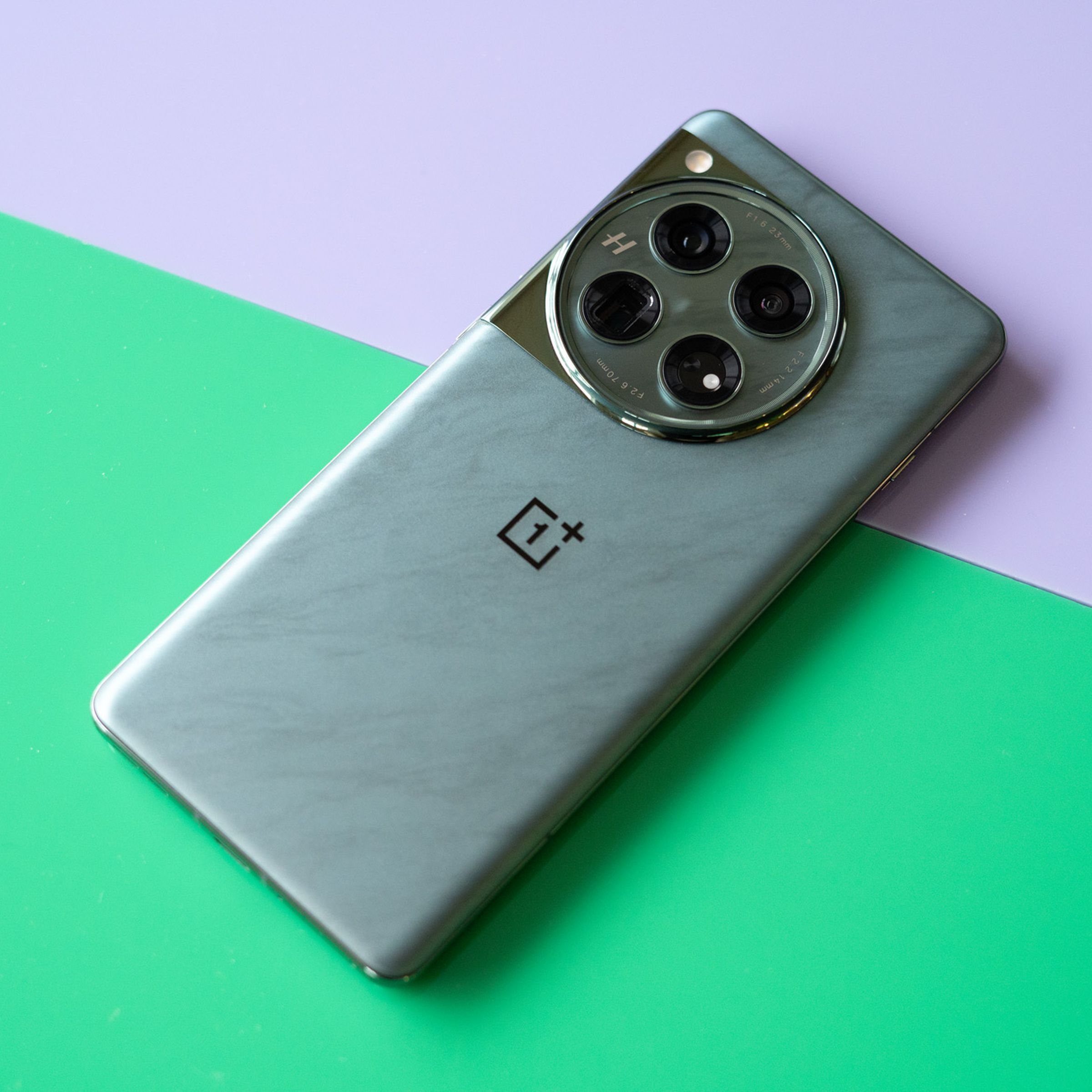 OnePlus 12 on a green and purple background showing back of the phone in marbled green color.
