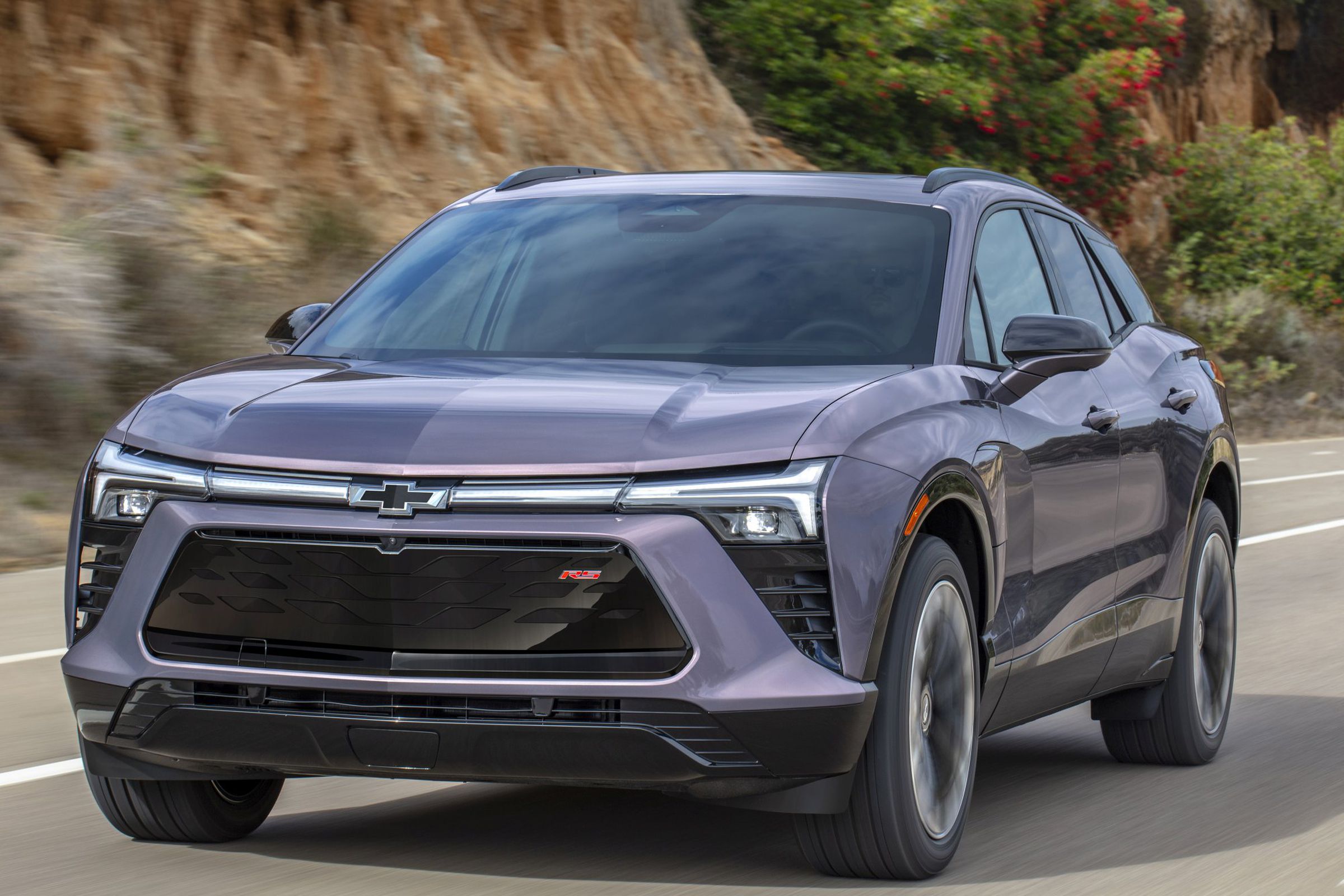 Front 7/8 view of the 2024 Chevrolet Blazer EV RS in Galaxy Gray Metallic driving down the road.