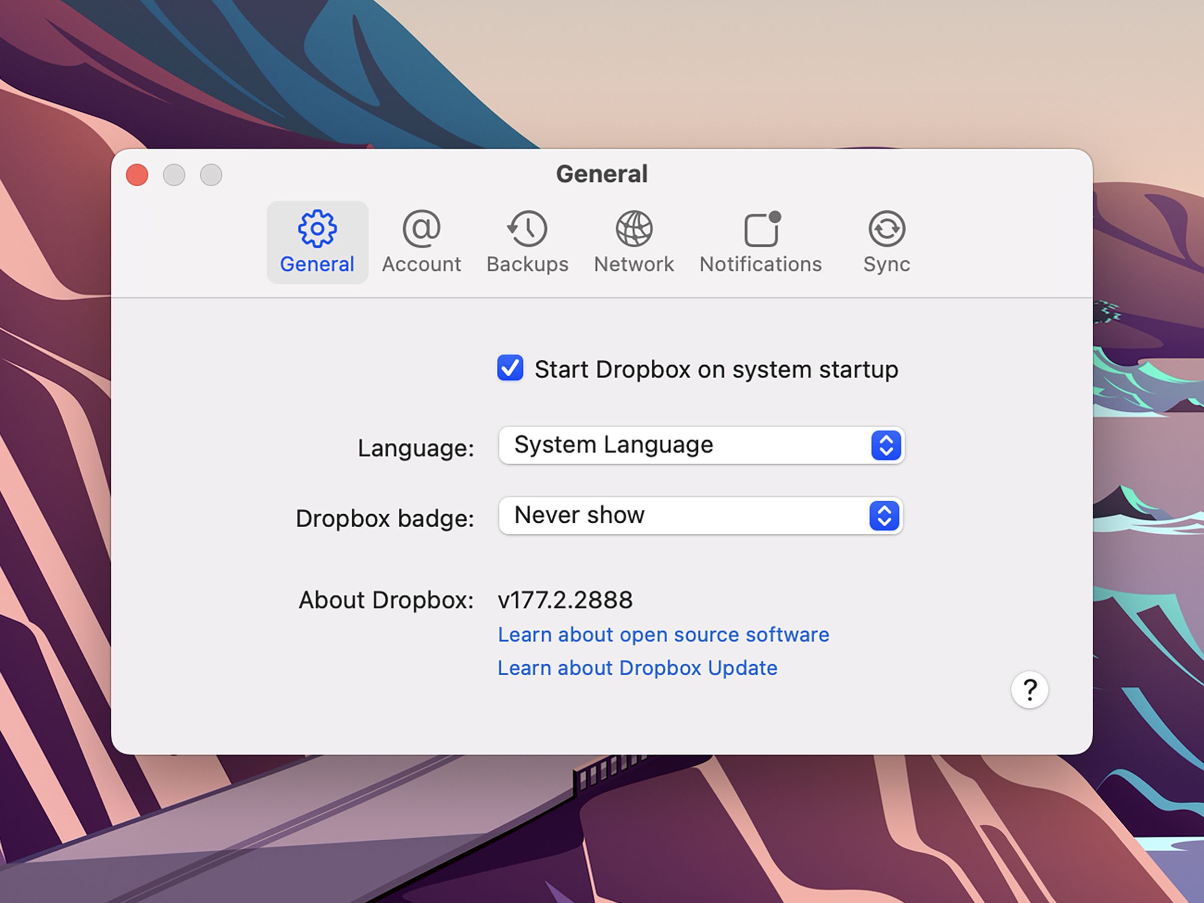 Window labeled General, with several icons below including General, Account, Backups, etc., and below that a checkbox next to Start Dropbox on system startup, and down-down menu selections for language, dropbox badge.