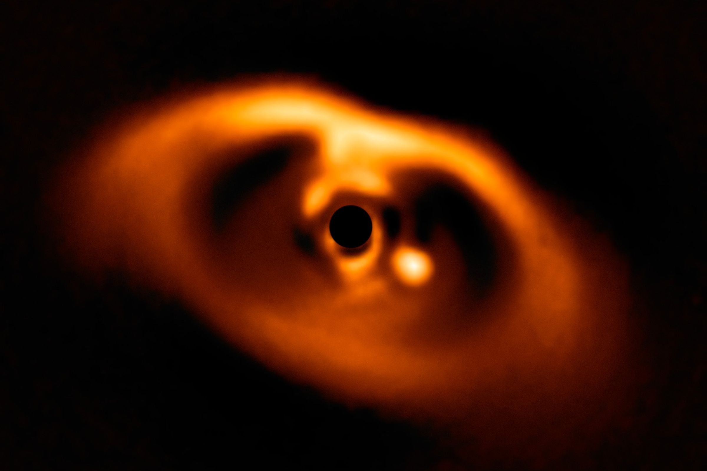 An image of the star PDS 70 and its protoplanetary disk. The new planet can be seen as a light circle to the right of the star, which has had its light block out.