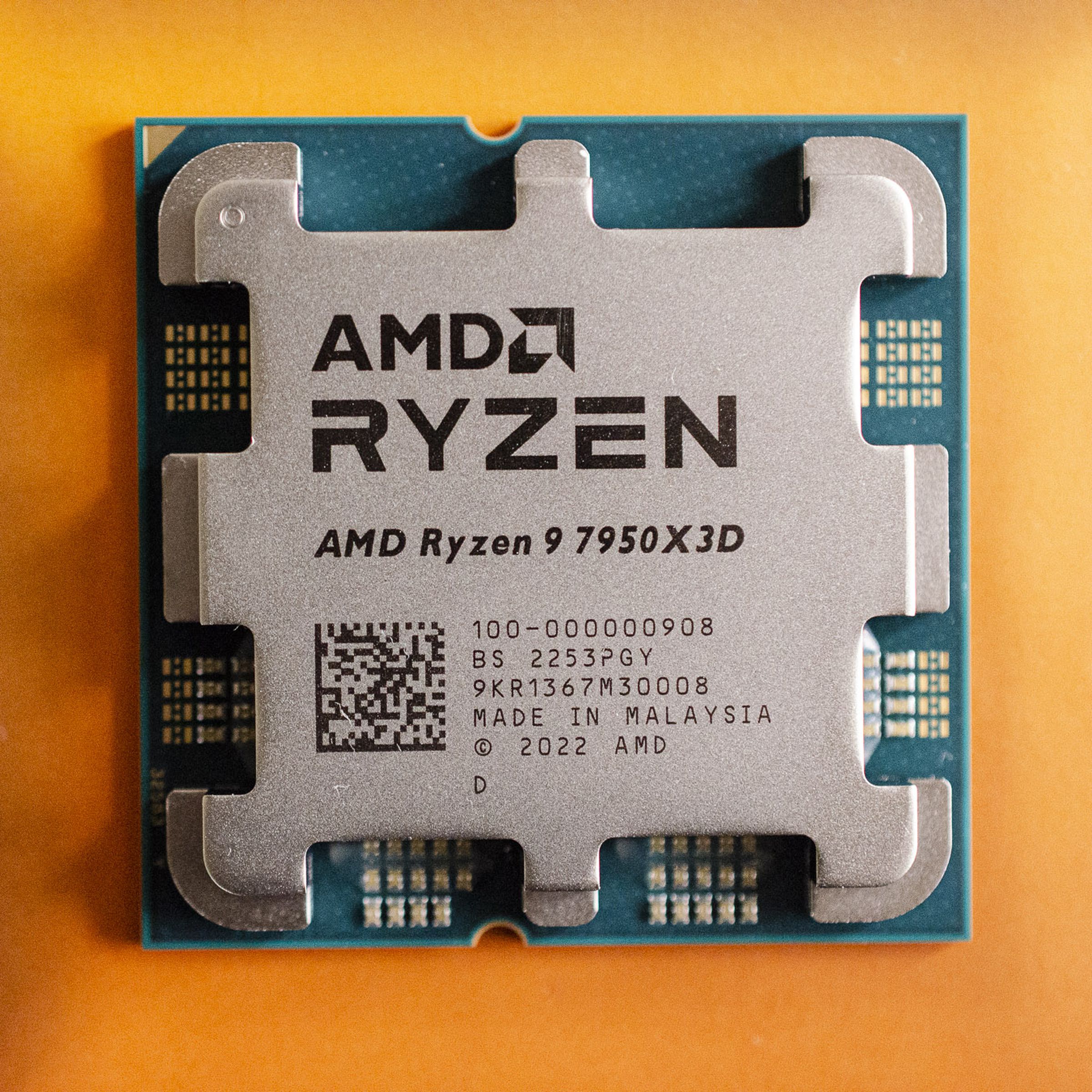 A close up photo of AMD’s new Ryzen 9 7950X3D processor on top of its orange box