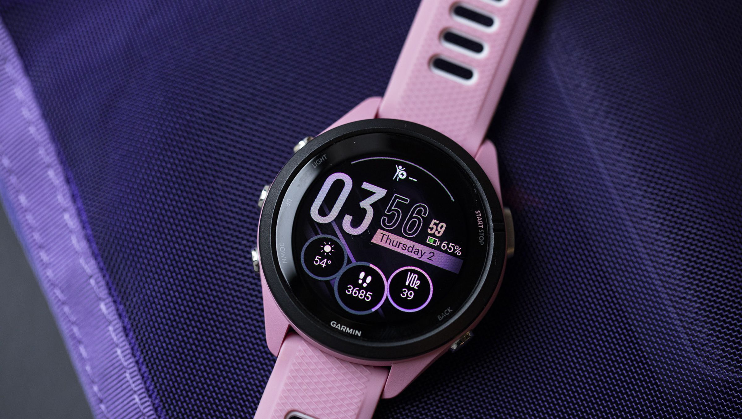 Close-up of the Garmin Forerunner 265S’s OLED display and watchface on a purple background