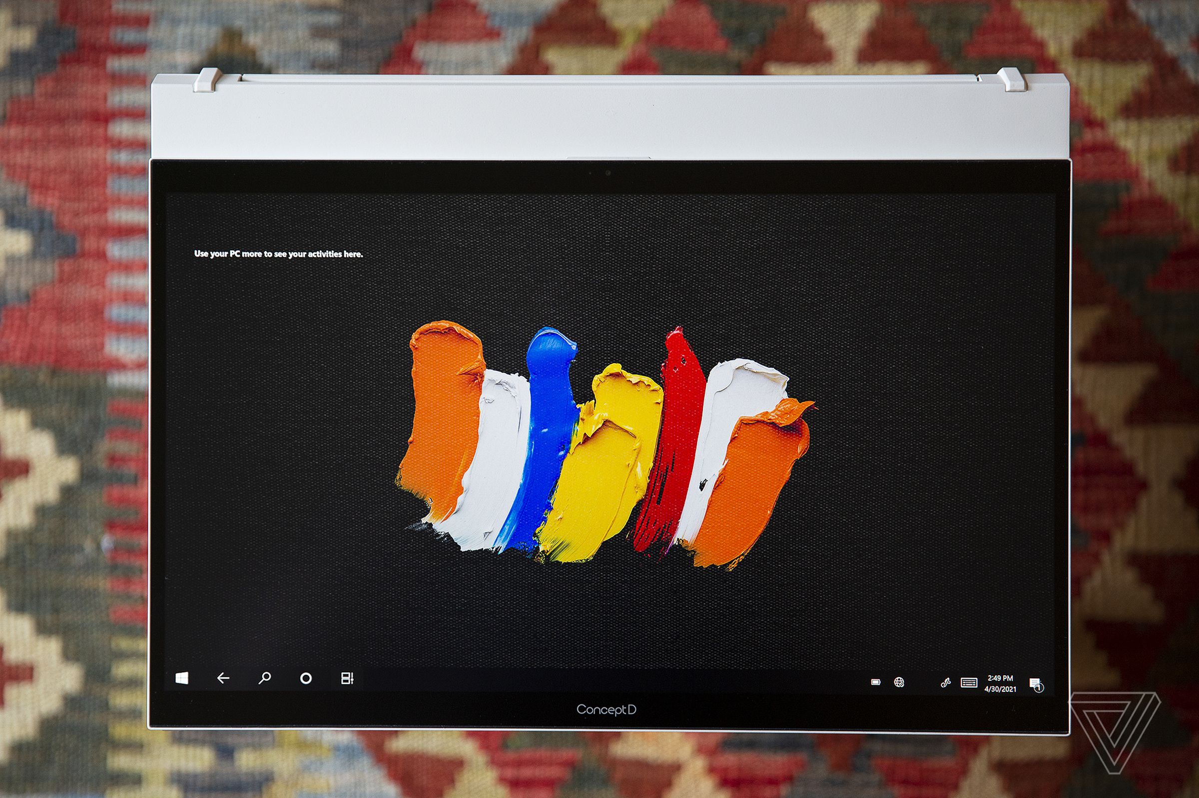 The Acer ConceptD 7 Ezel in Tablet Mode on top of a rug. The screen displays multicolored paint strokes on a black background.