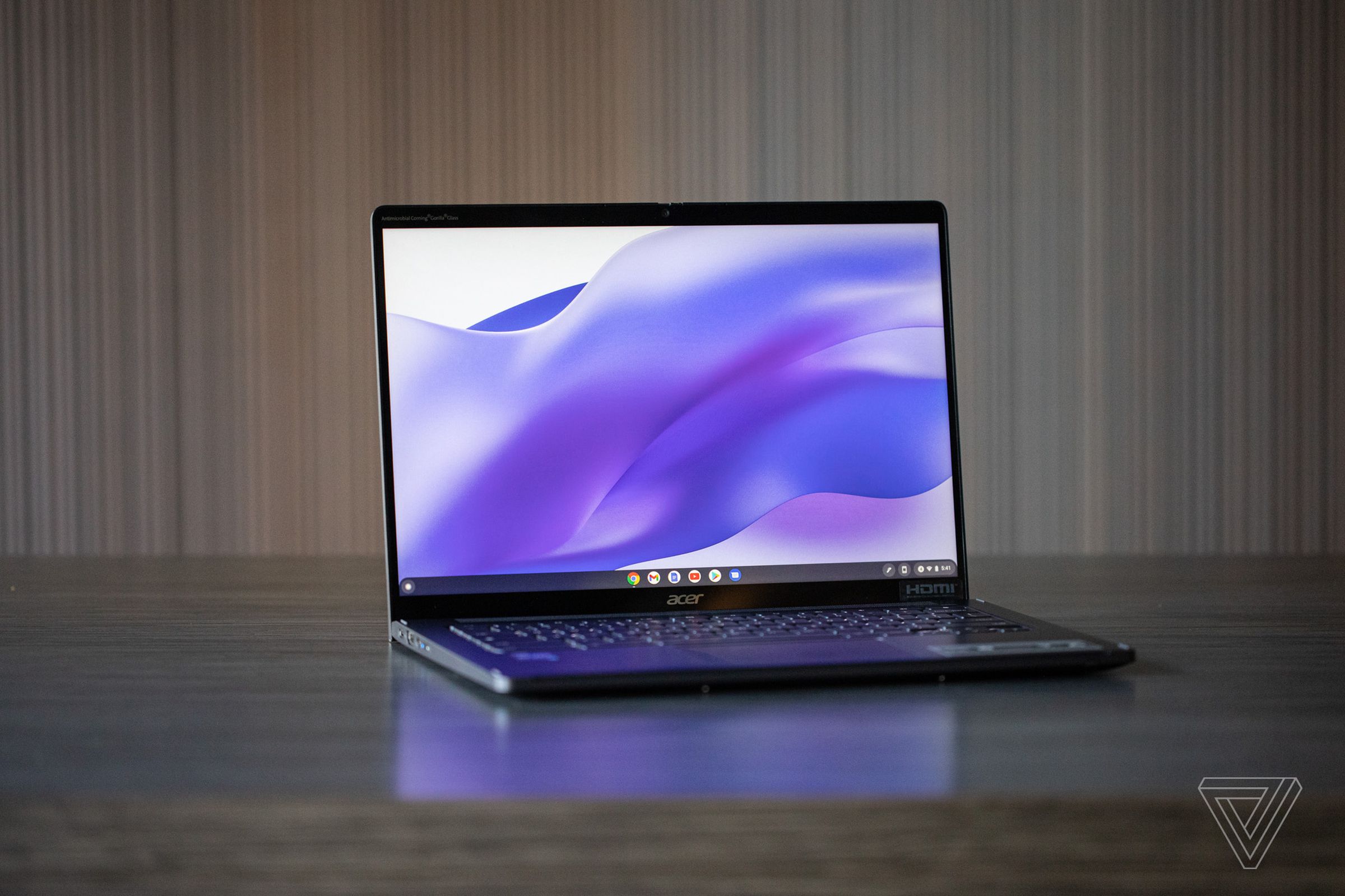 The Acer Chromebook Spin 714 open on a table displaying a purple ribbon desktop background.