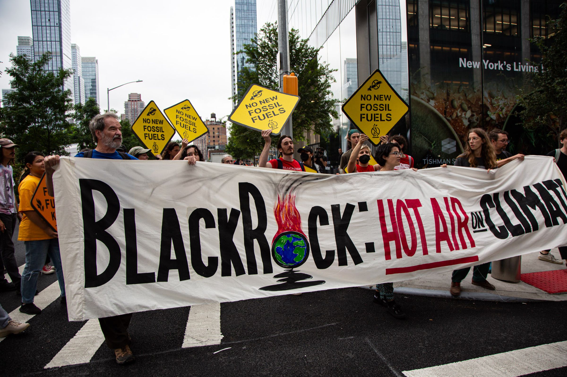 A group of people hold a banner that says, “BlackRock: Hot Air on Climate.”