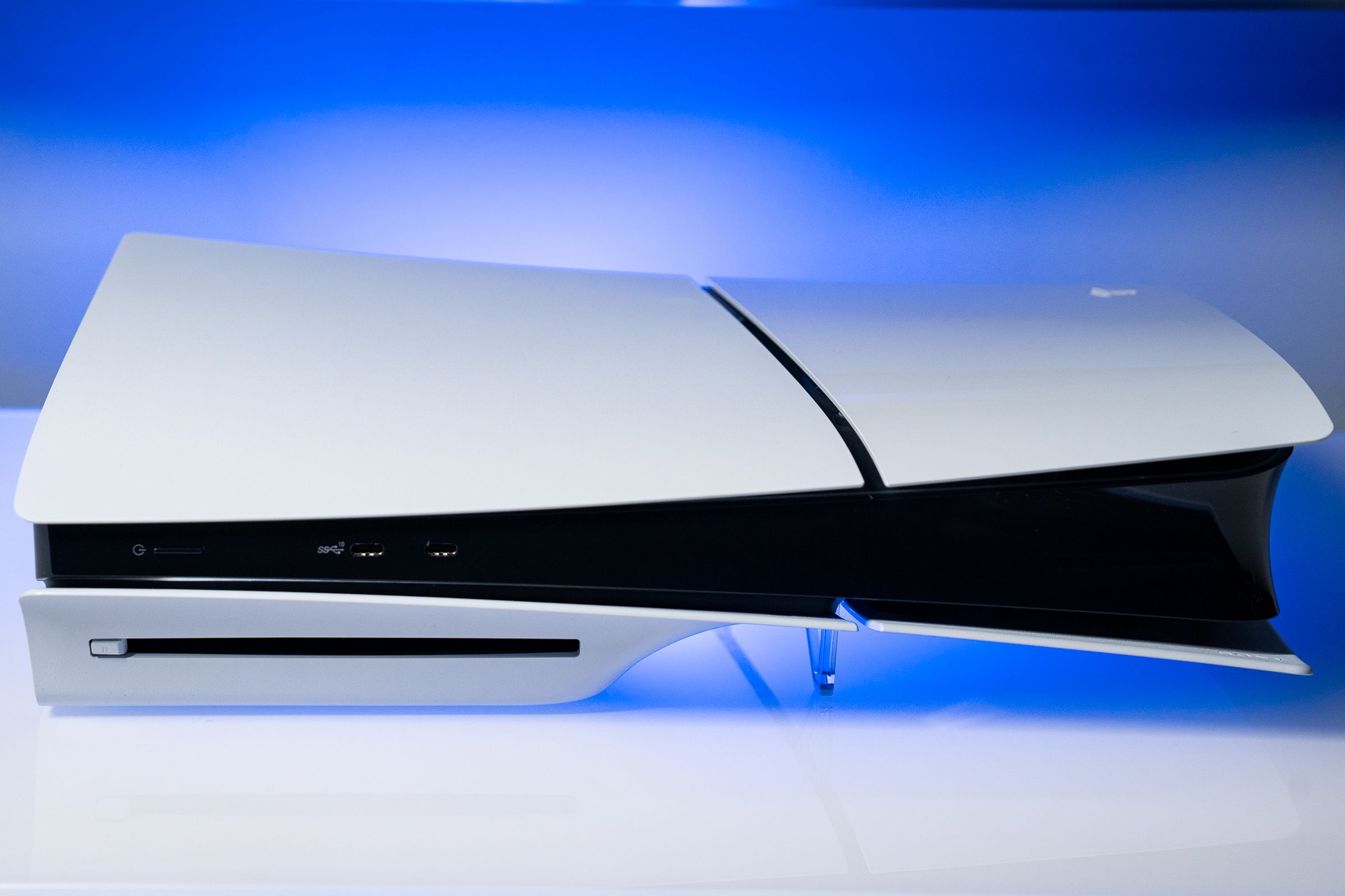 The PlayStation 5 slim sitting on a white surface with a blue backlight.